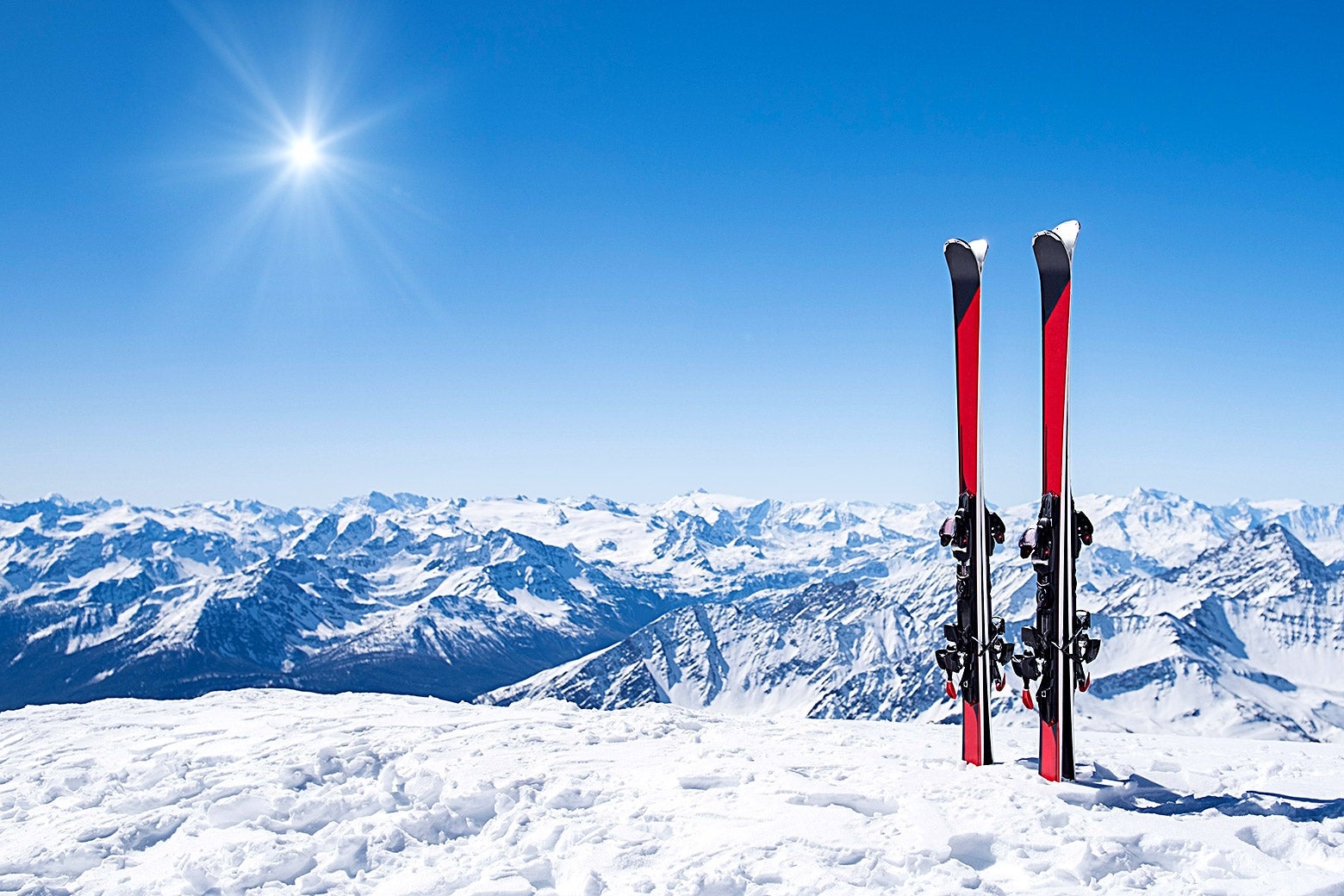 Two pairs of skis are seen standing upright near the edge of a snowy hill.