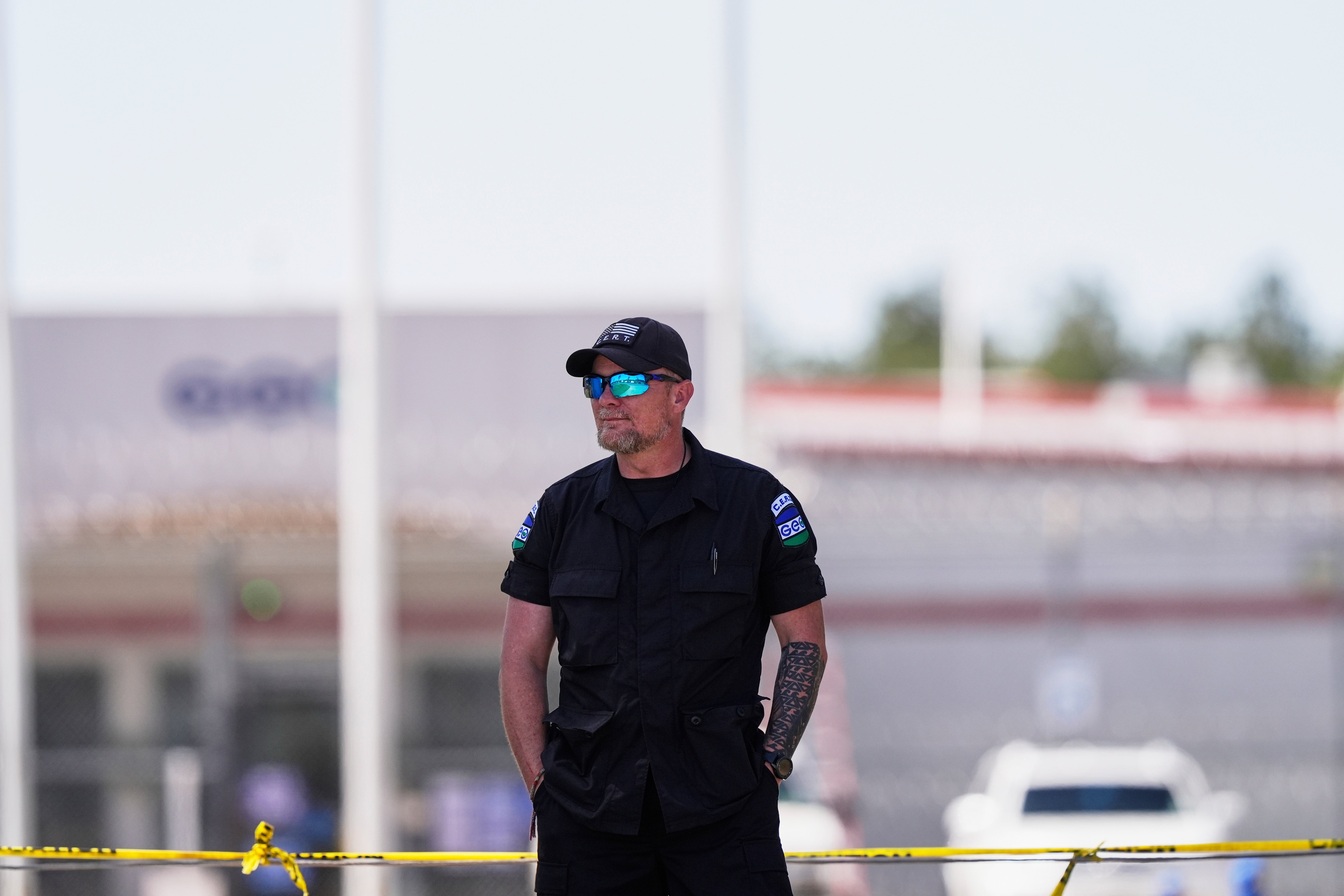 A bearded white man in a black uniform that reads "GEO" wears sunglasses and stands outside.