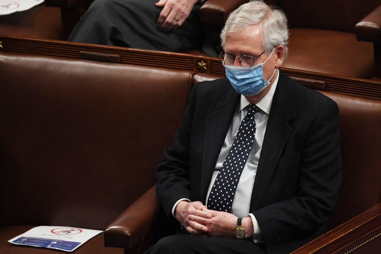 Mitch McConnell, wearing a mask, sits with his hands folded in his lap