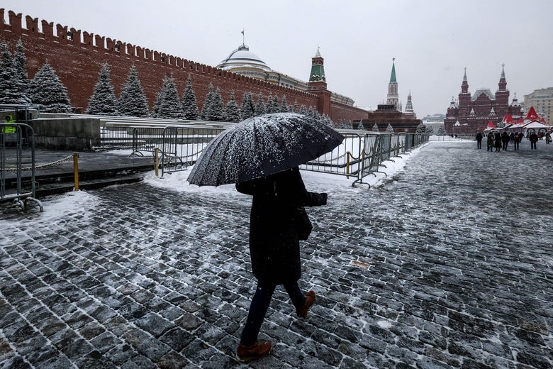 A woman with an umbrella walks on Red Square past the Kremlin after a night of heavy snowfall.