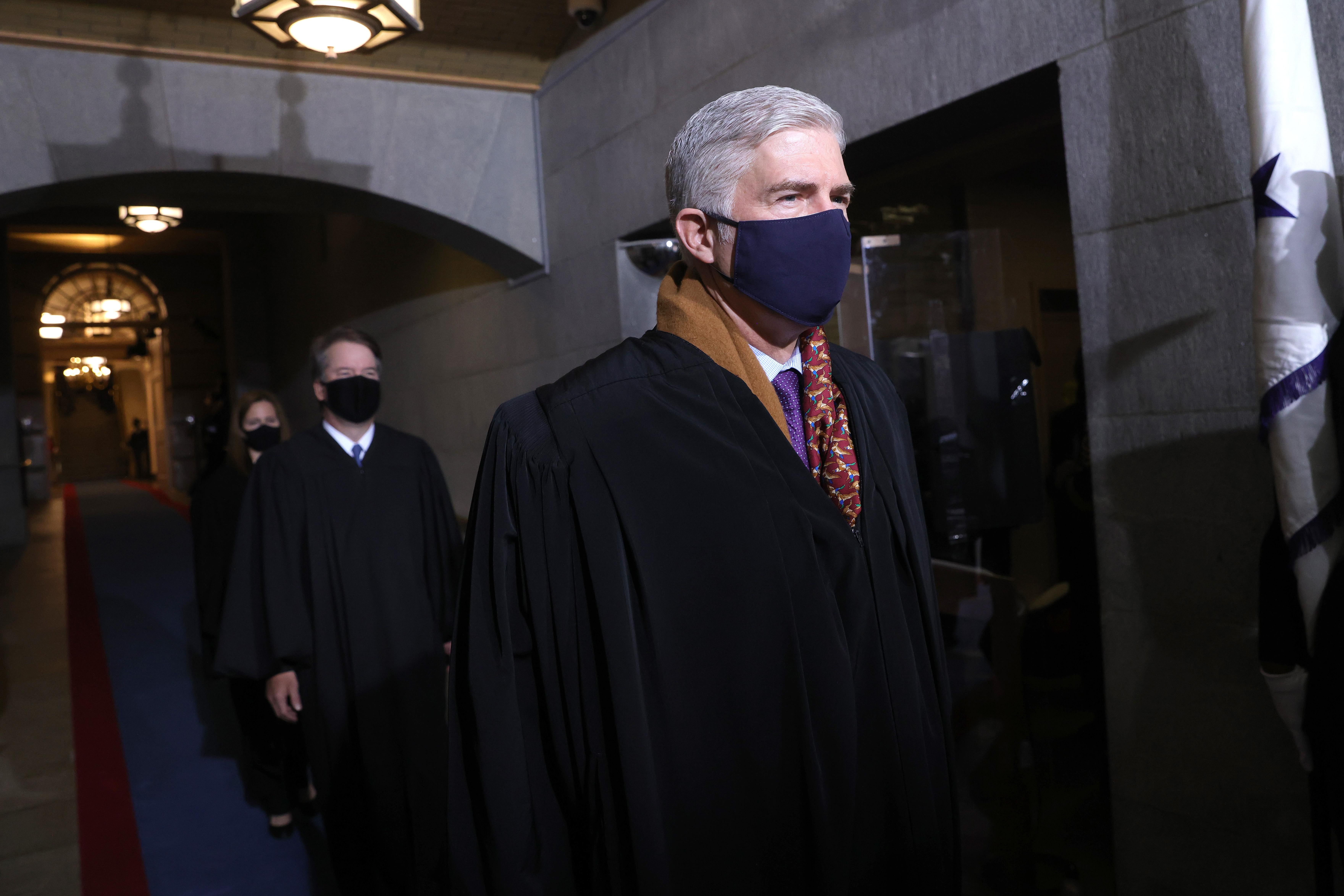 Gorsuch wears a blue mask and a very handsome orange scarf and purple tie under his robe. 