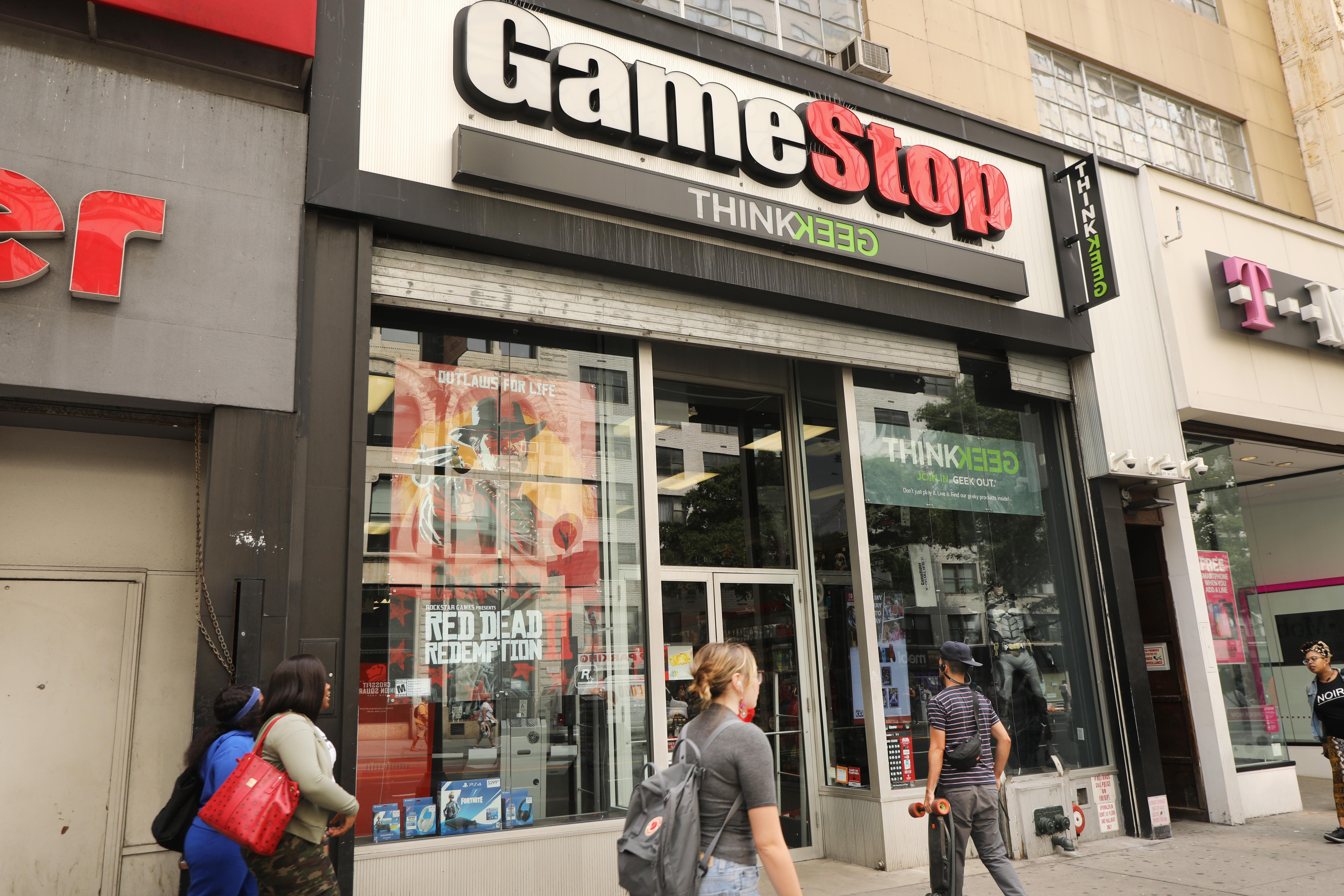 People walk by a GameStop storefront.