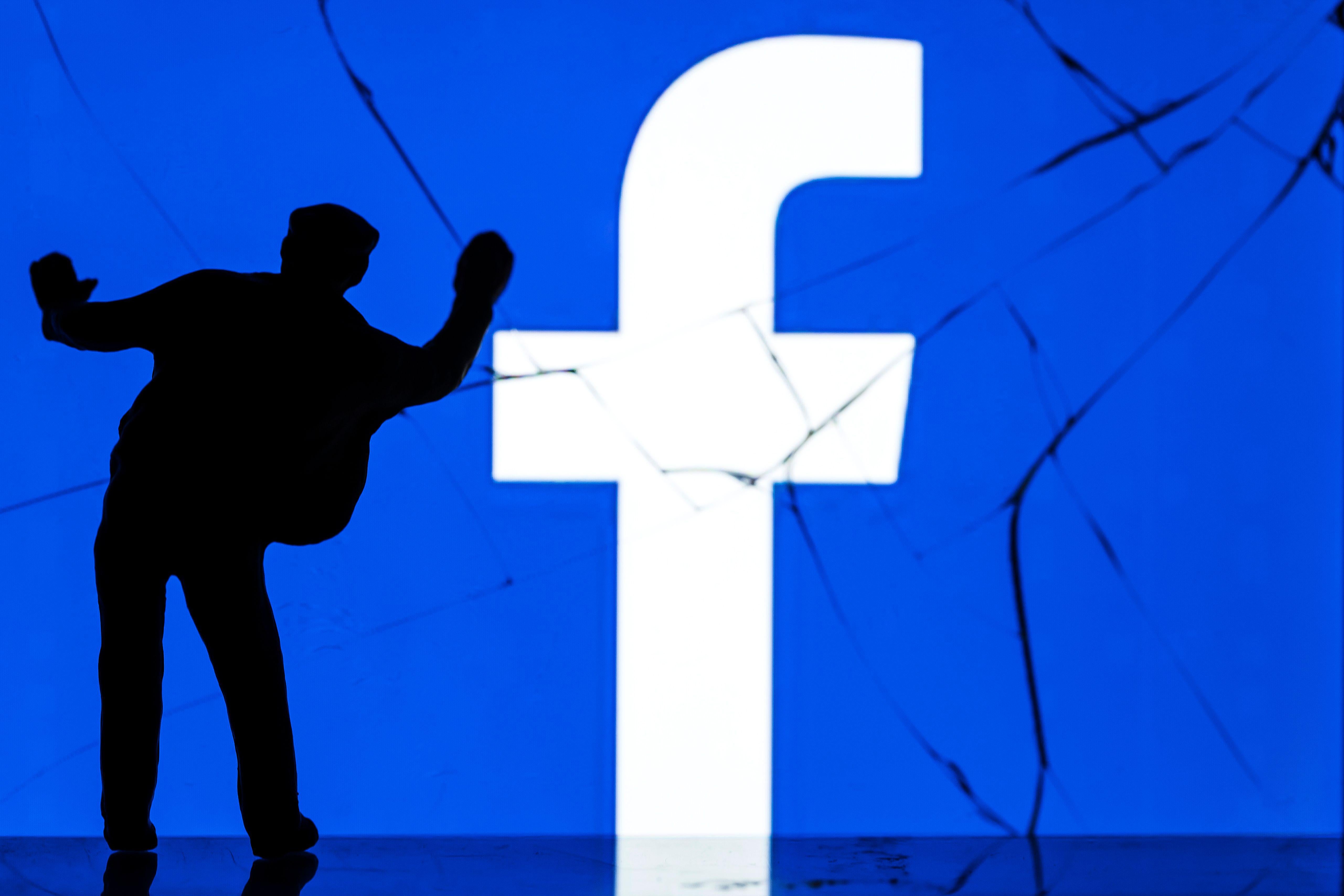 A figurine standing in front of the Facebook logo.