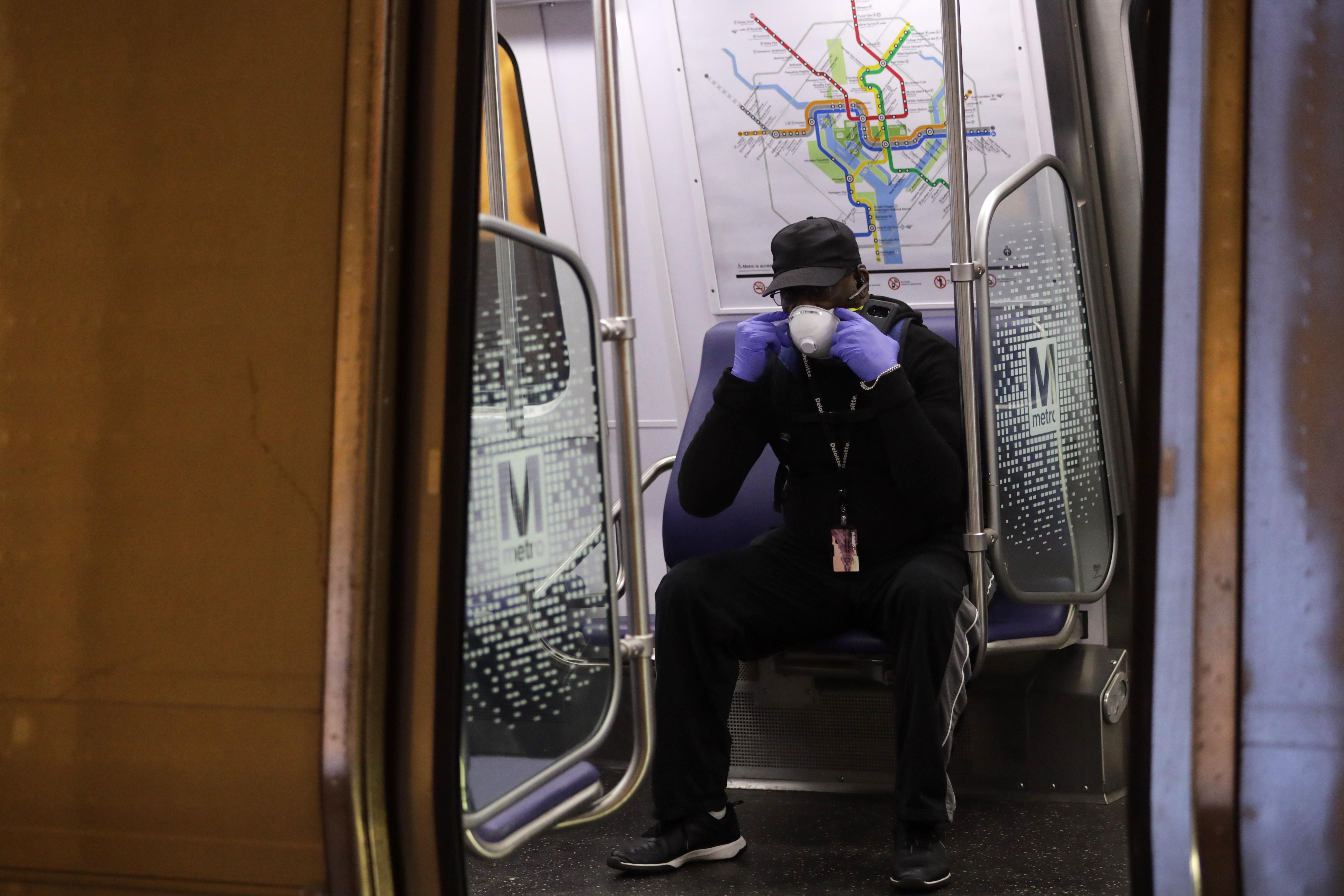 A passenger adjusts his mask in a Metro train car.