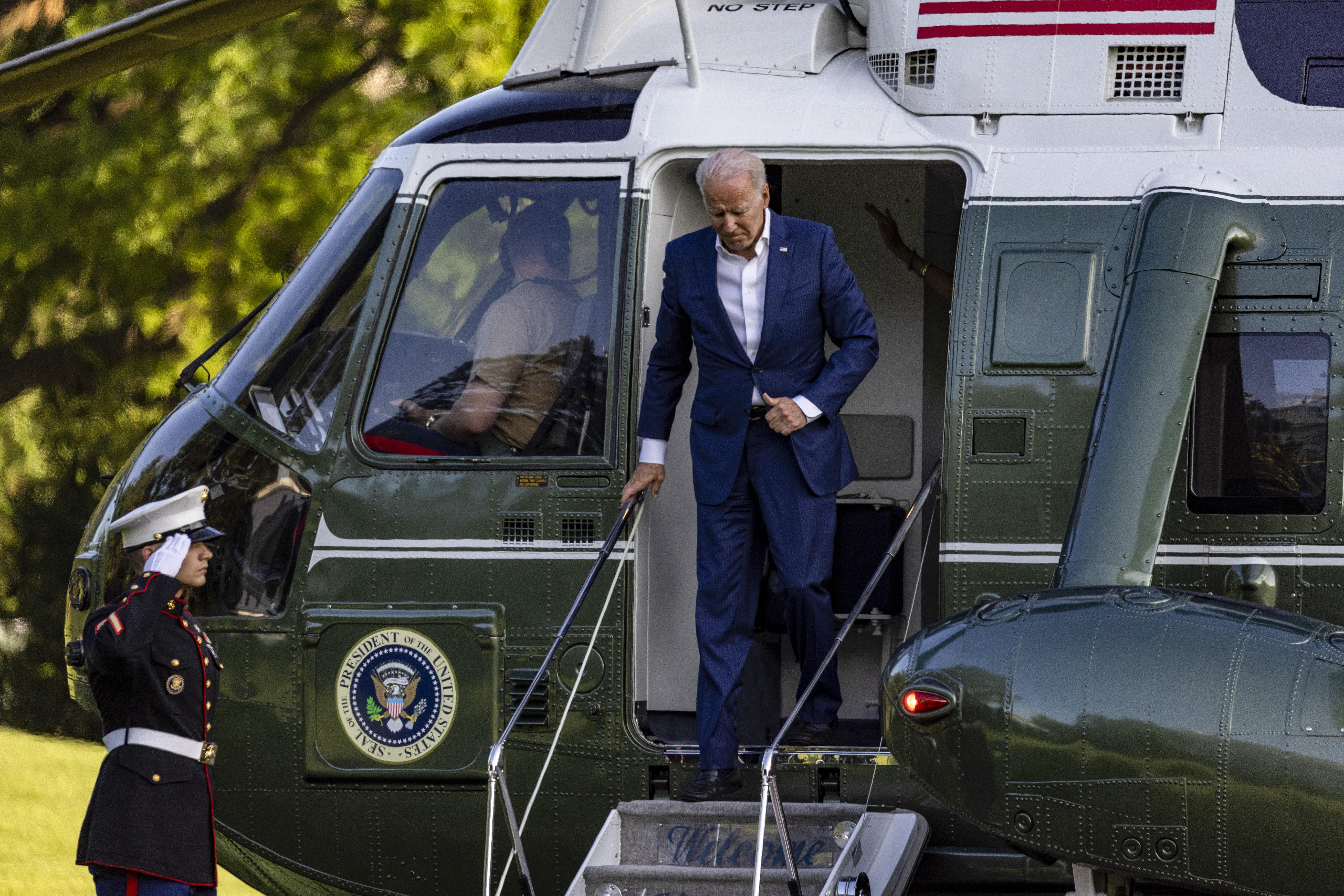 Biden stepping off a helicopter onto a staircase. 
