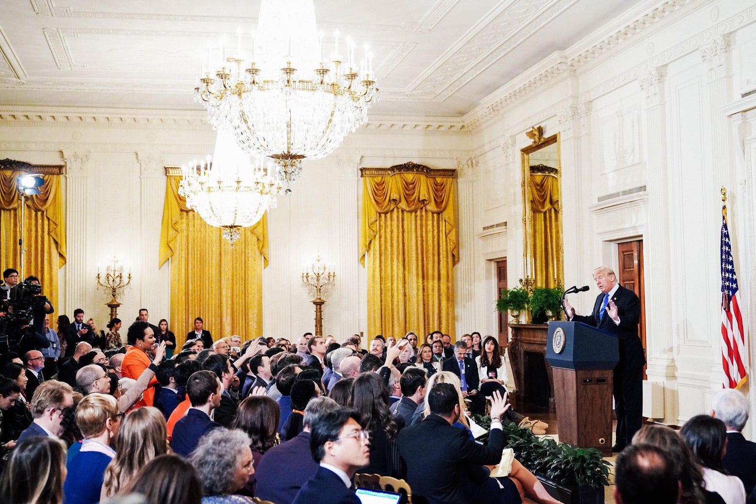 Trump speaking in a room full of reporters.