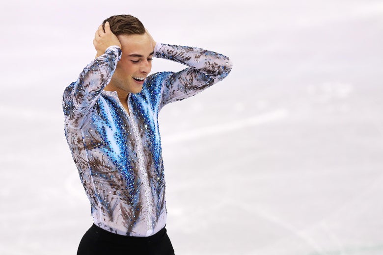 Skater Adam Rippon clutches his head in celebration on the ice.