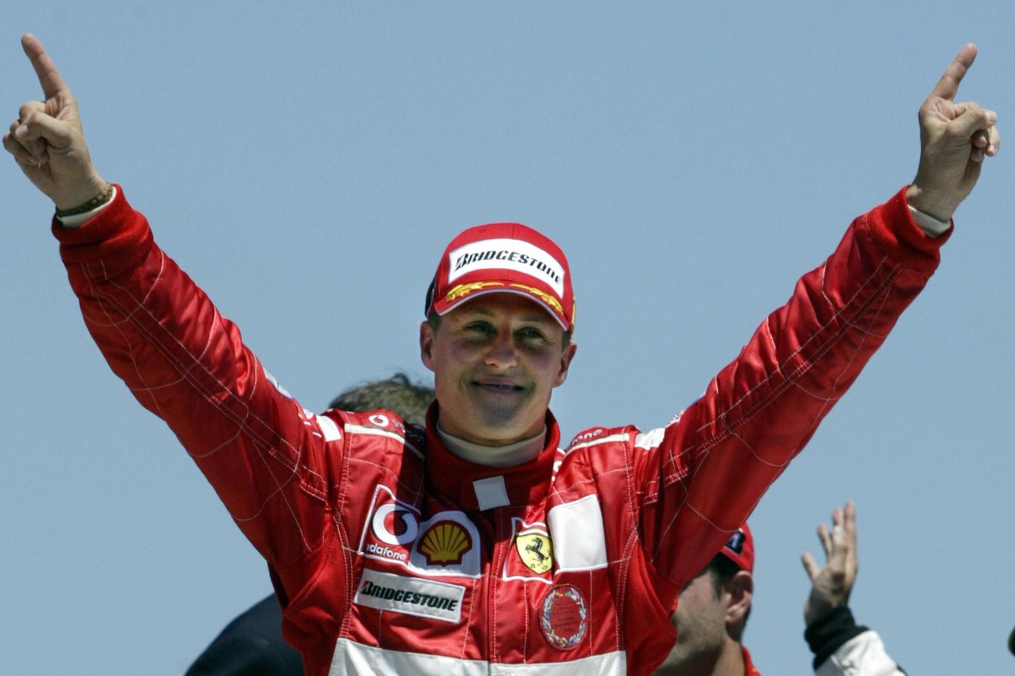 Schumacher smiles and raises his arms and pointer-fingers in celebration
