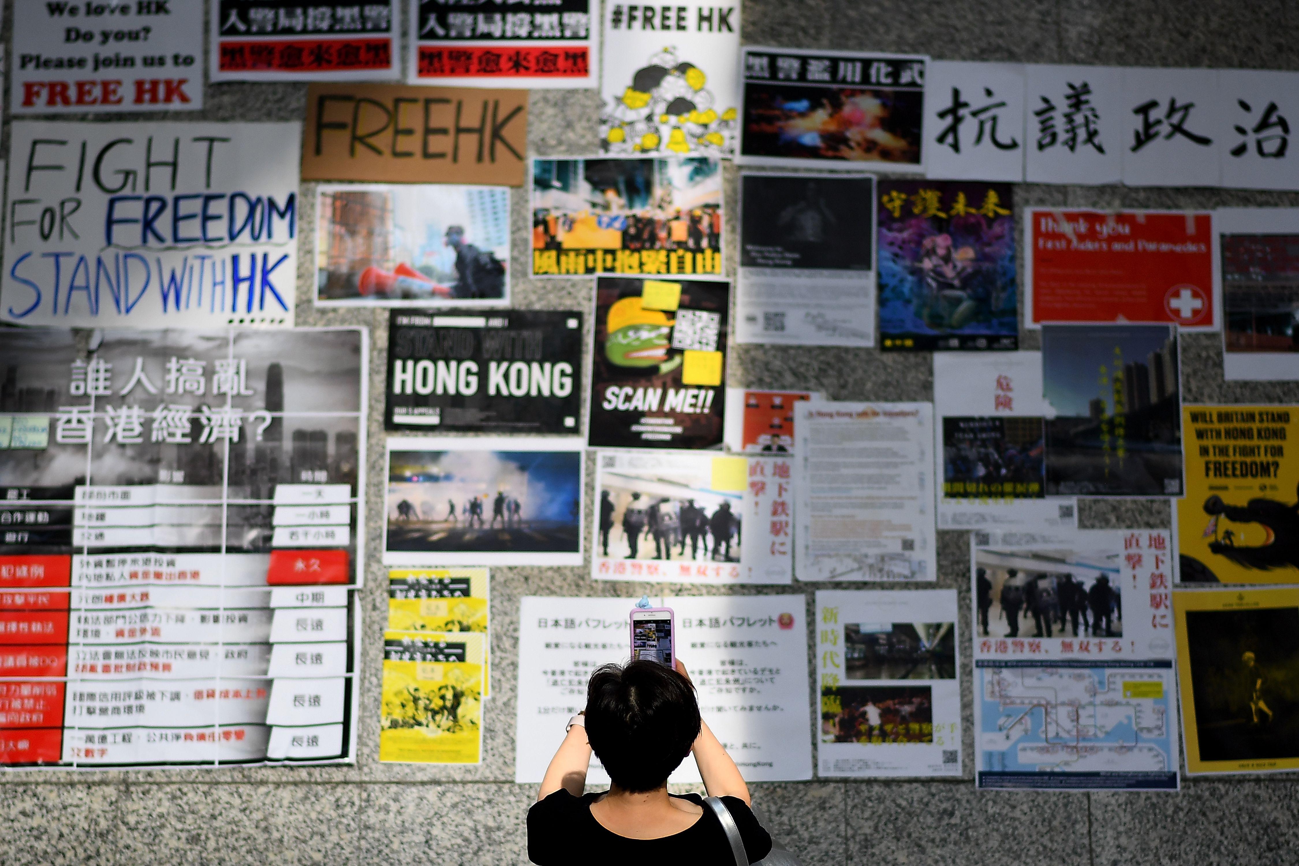 A woman takes photographs of messages by Pro-Democracy protesters at the airport.