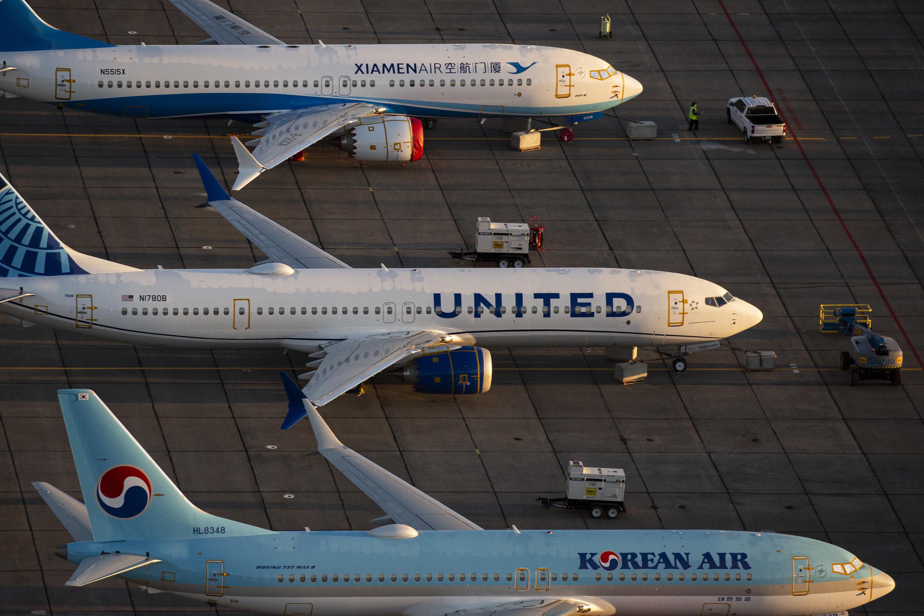 Three Boeing 737 Max airplanes are parked side by side on the tarmac.