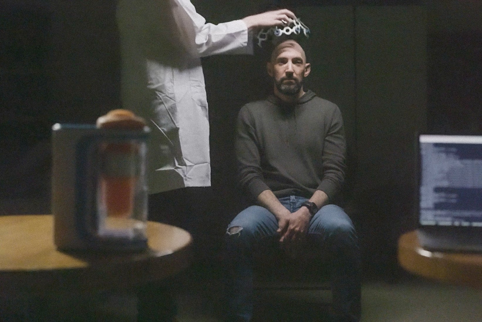 A man in a darkened room in an EEG cap. 