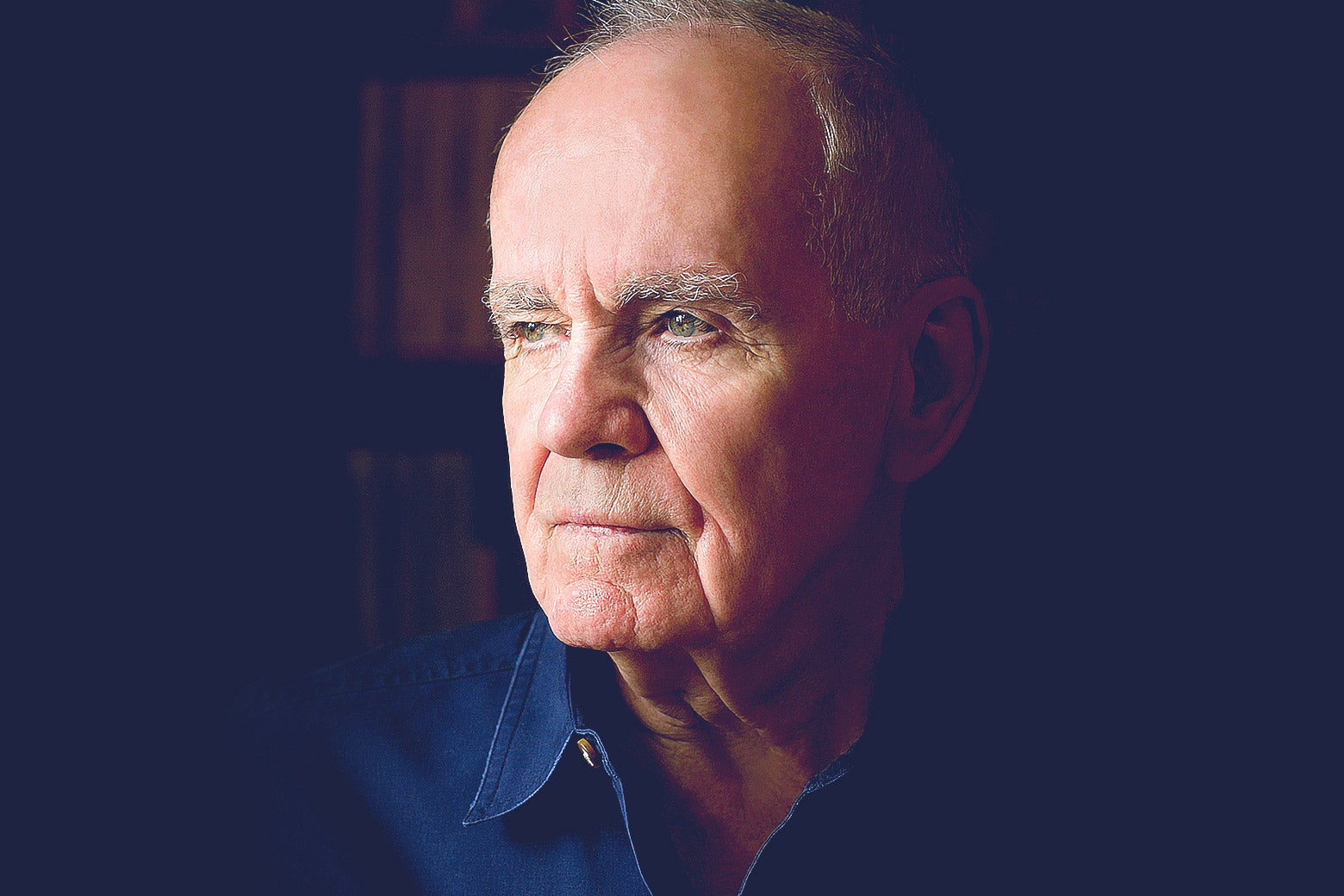 Cormac McCarthy in a collared blue shirt looking off into the distance.