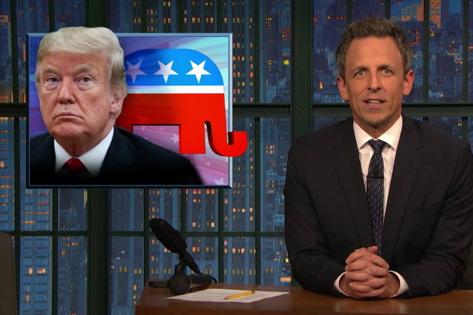 Seth Meyers, in front of a picture of Donald Trump.