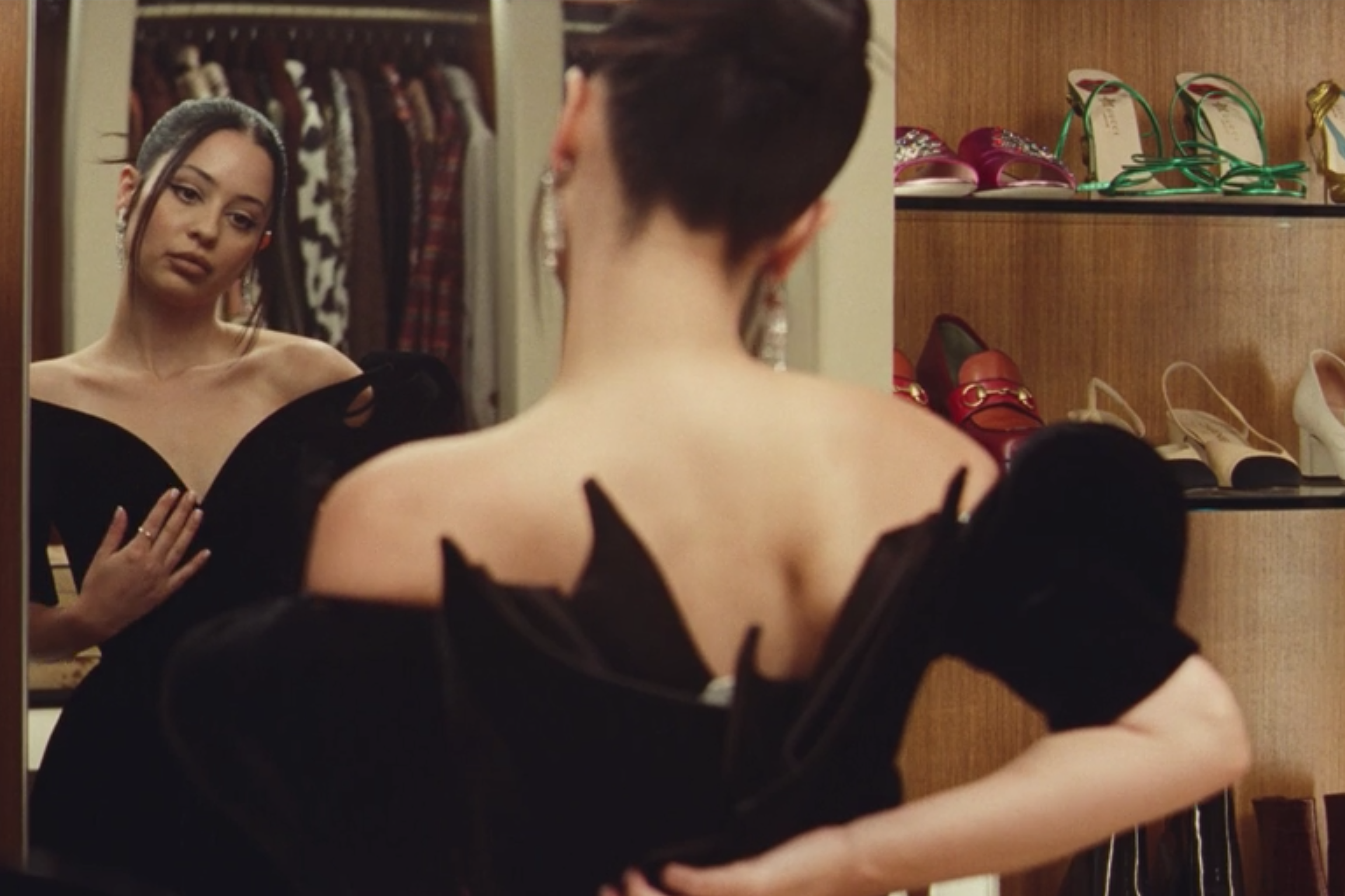 A girl tries on a black dress and looks at herself in the mirror.