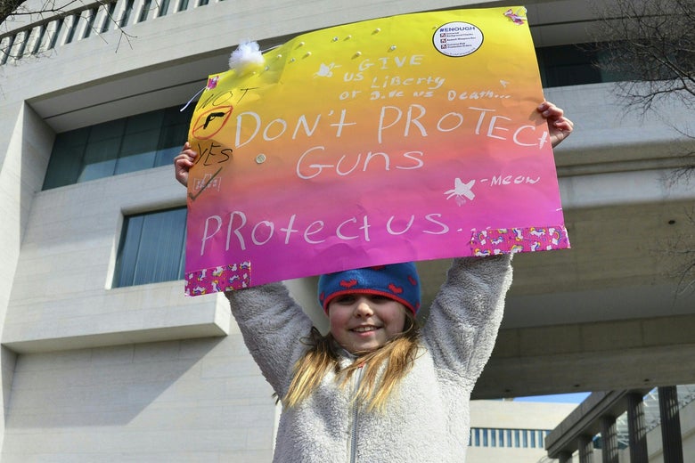 A little girl hoists a placard reading, "Don't protect guns protect us."