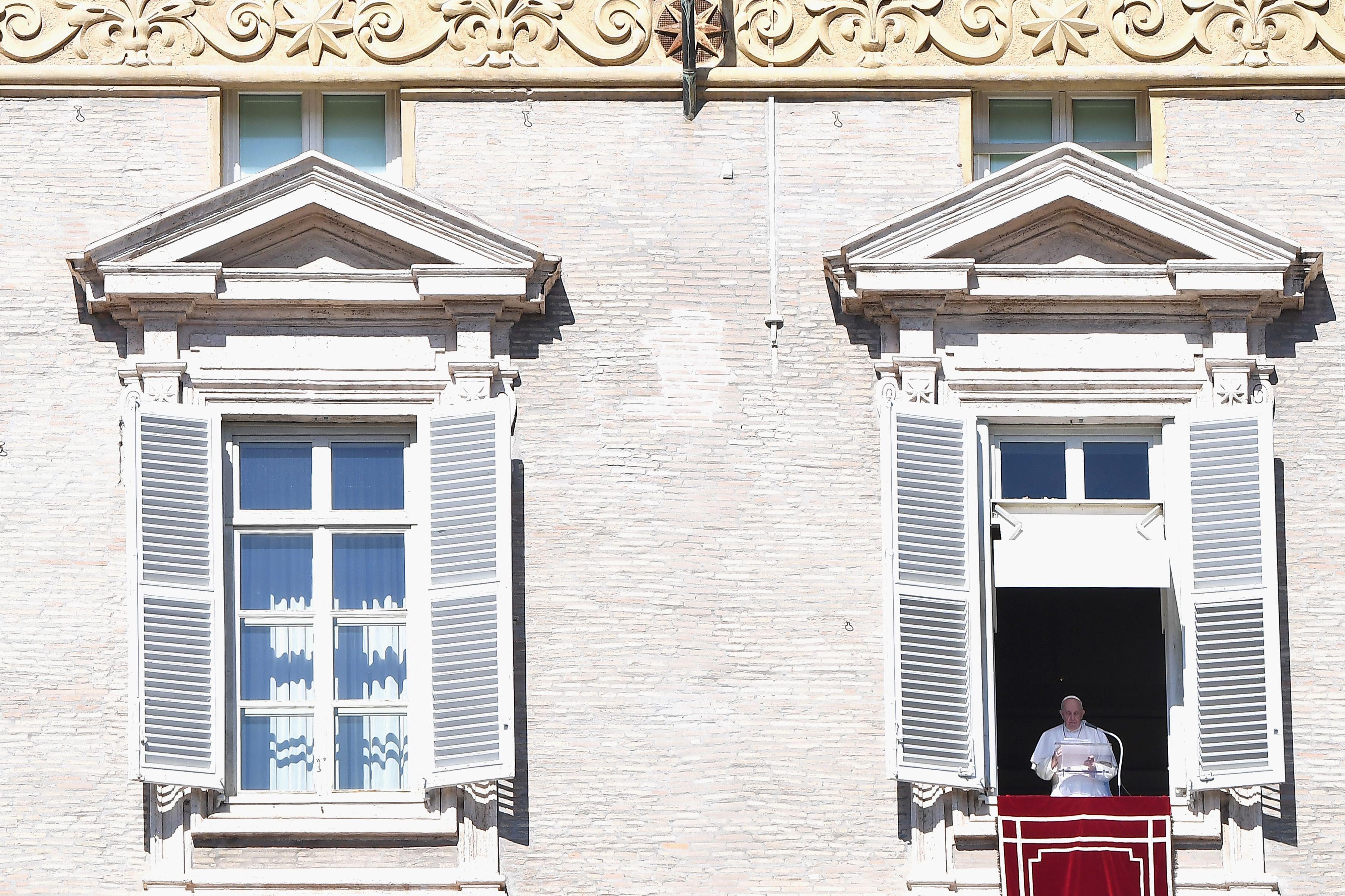Pope Francis speaks at a lectern from a window overlooking St. Peter’s Square