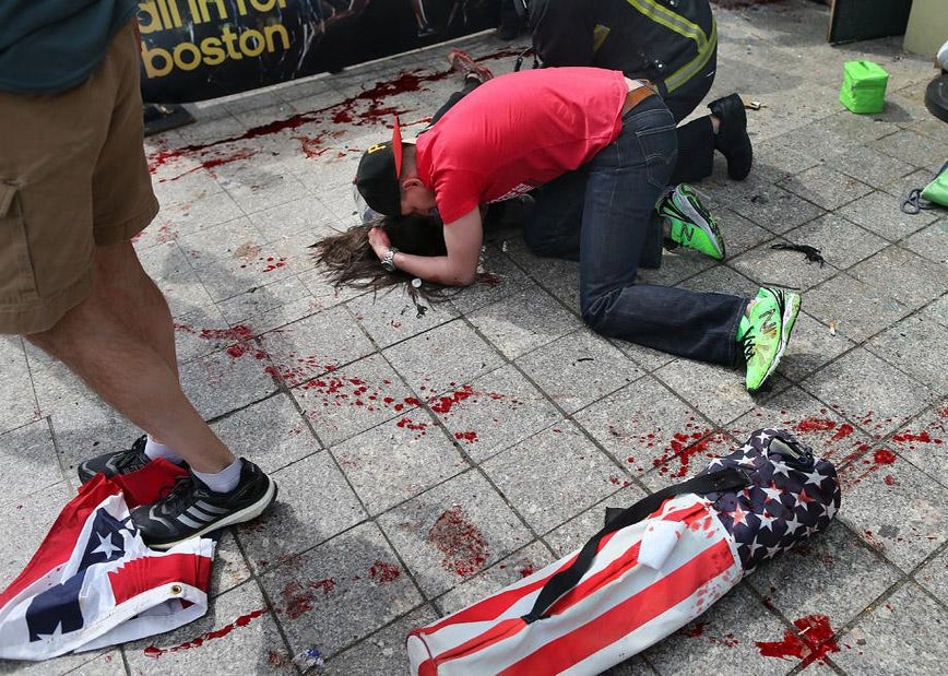 A man comforts a victim on the sidewalk at the scene of the first explosion near the finish line of the 117th Boston Marathon. 