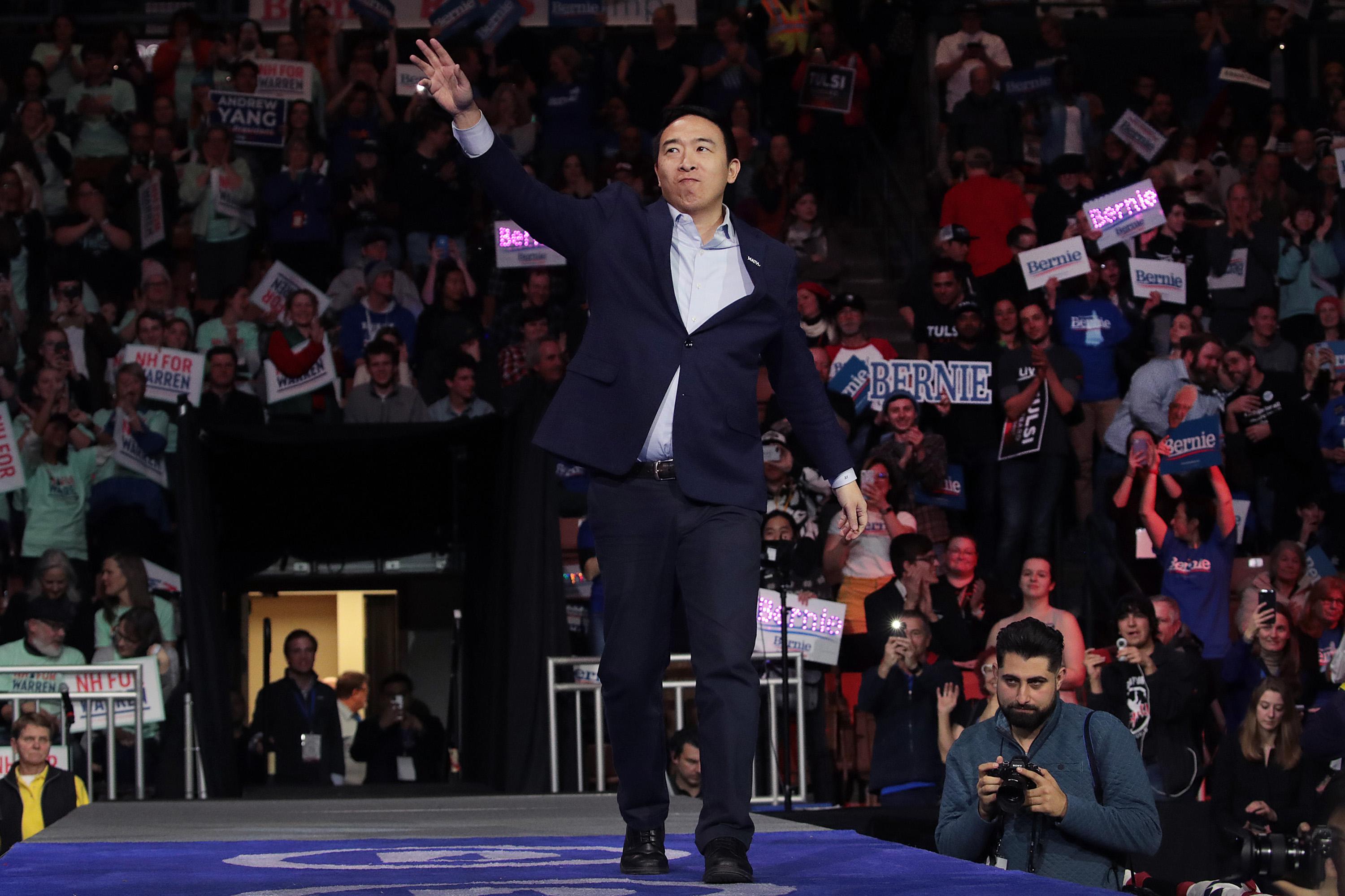 Democratic presidential candidate Andrew Yang on stage waving to a crowd.