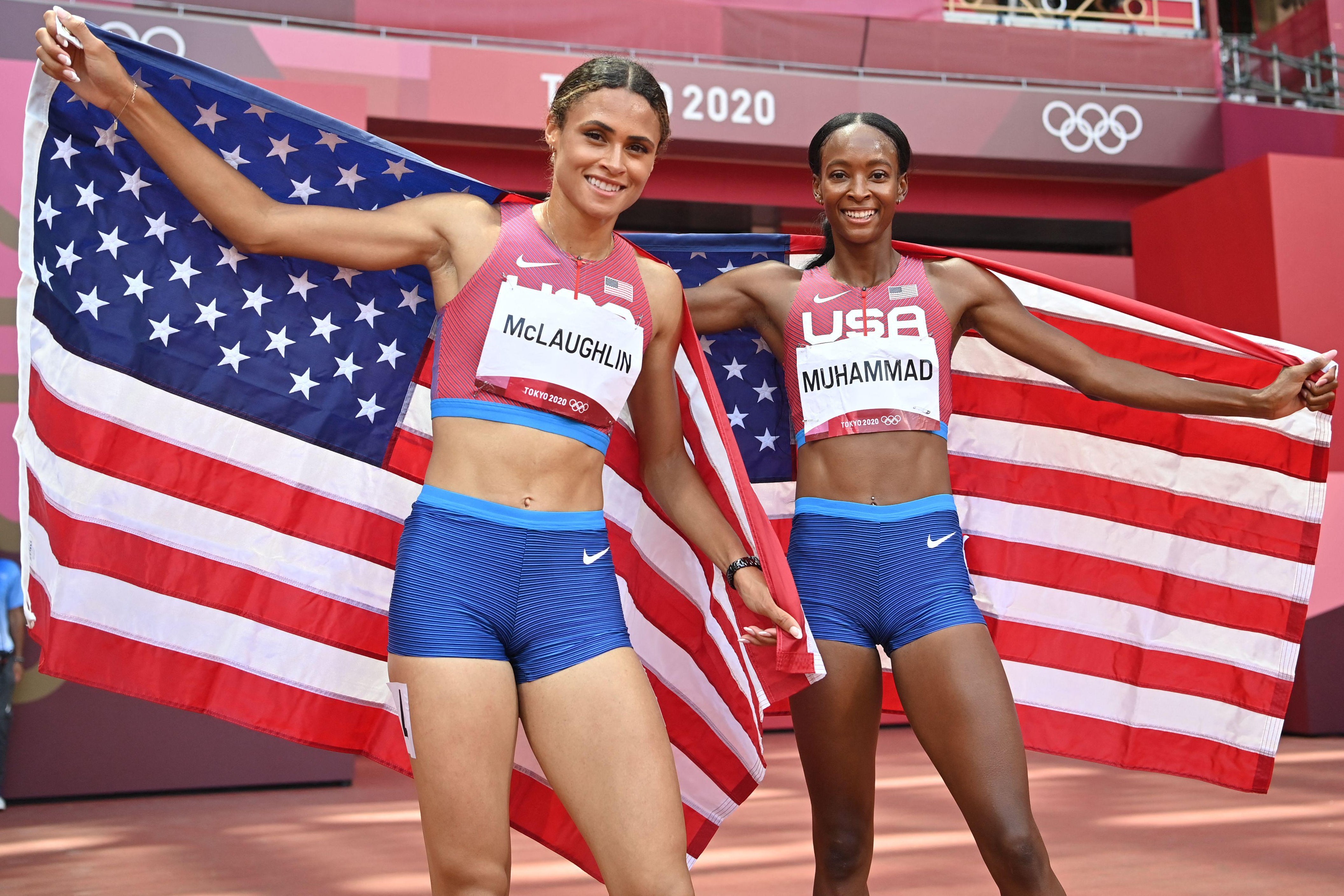 McLaughlin and Muhammad smile and drape American flags behind them on the track
