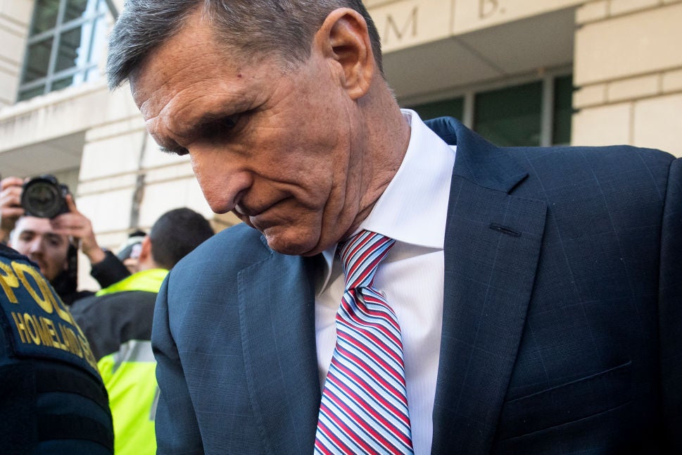 Flynn, wearing a suit, looks downward.