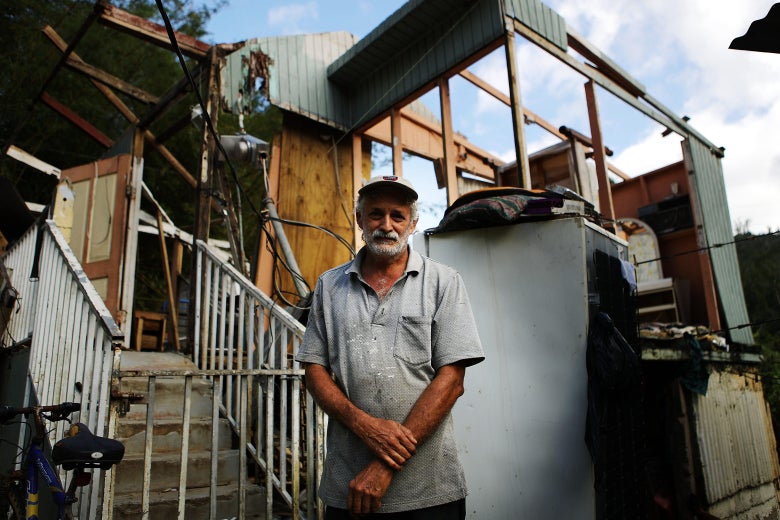 An older man stands in front of his destroyed home.
