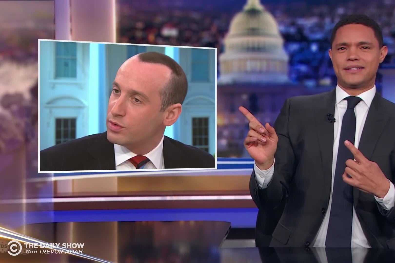Trevor Noah, looking in confusion at a picture of Stephen Miller's strange hairstyle.
