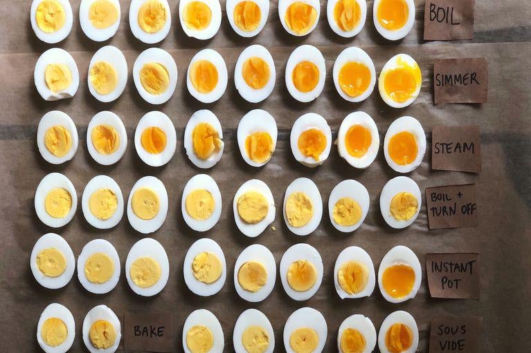 Dozens of halved, hard-boiled eggs lined up on a table. The egg yolks range from yellow and stiff to orange and runny.