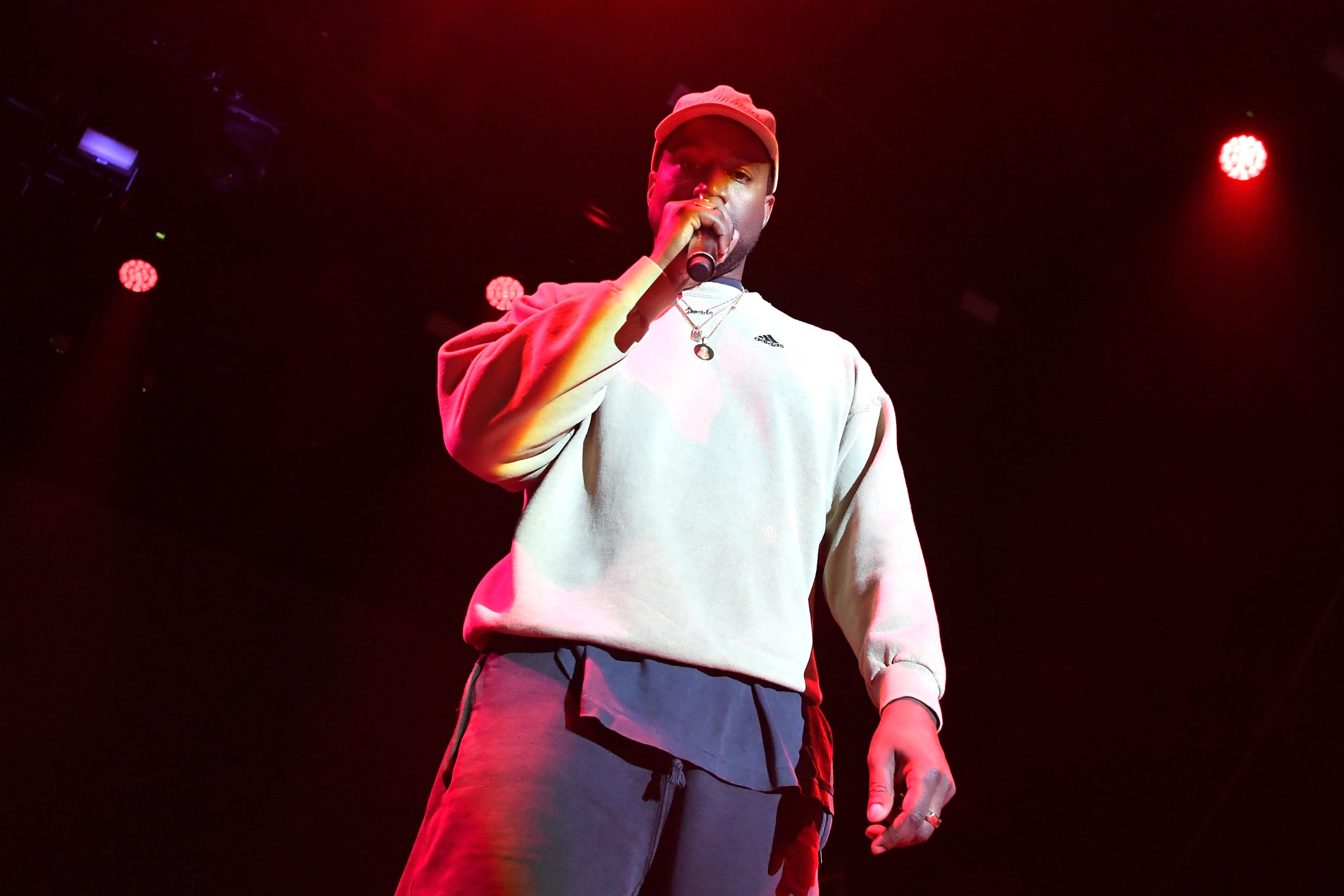 Kanye West holds a microphone onstage.