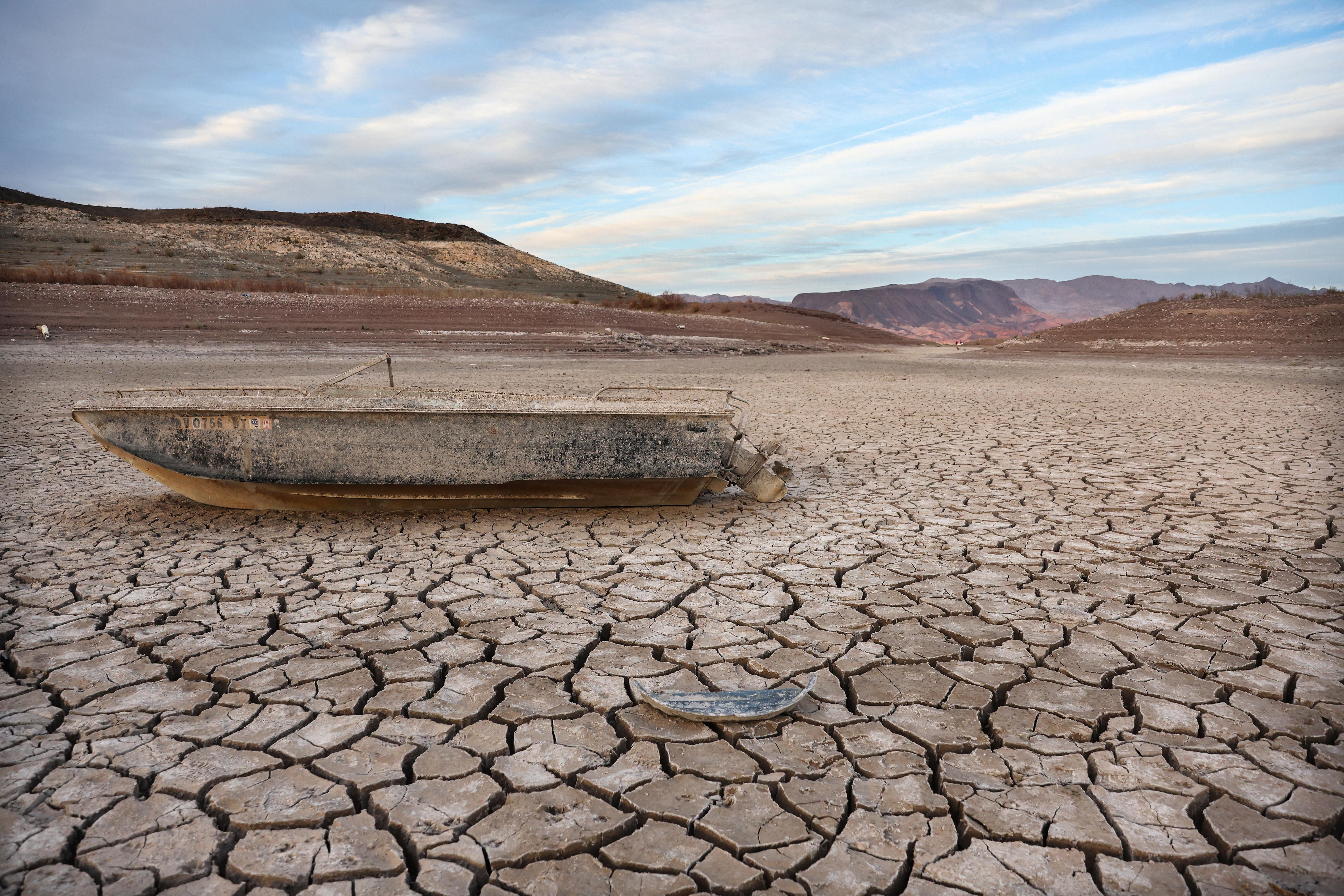 A boat sits on a cracked portion of dry land.