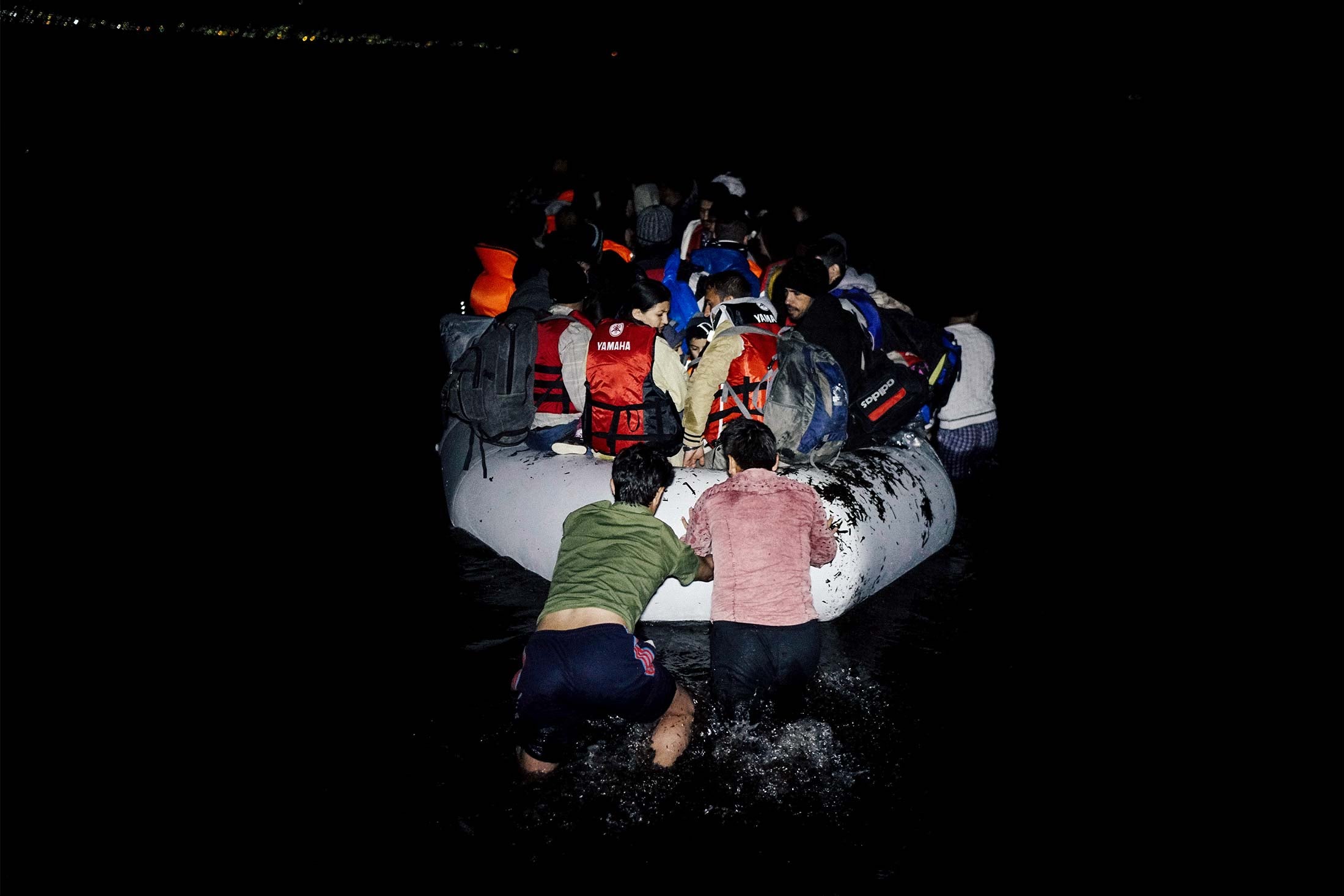 Refugees on a dinghy in the dark.