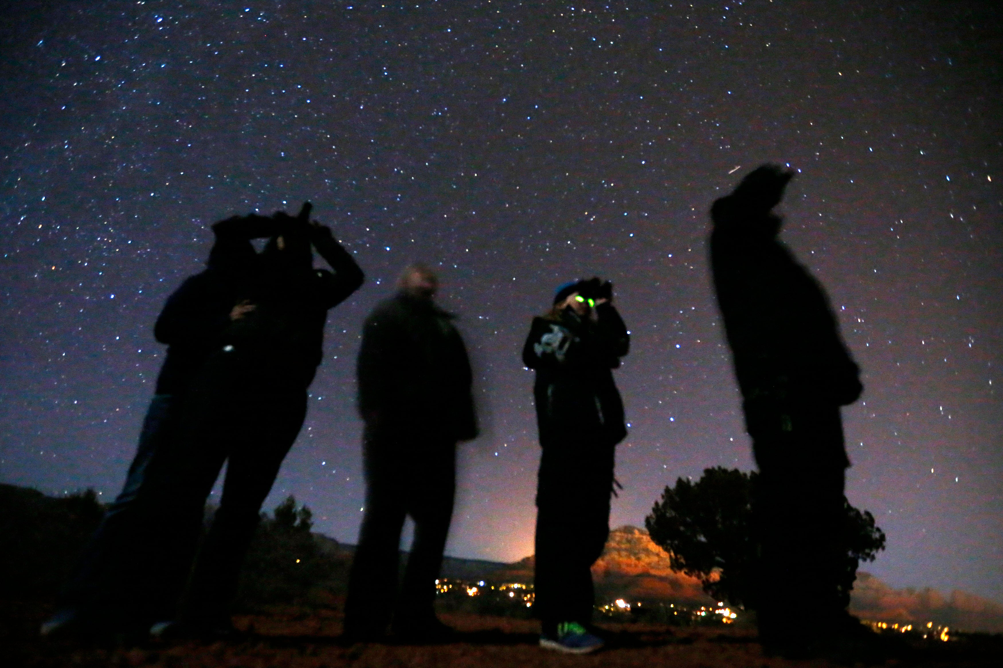 People standing under a night sky, looking through goggles.