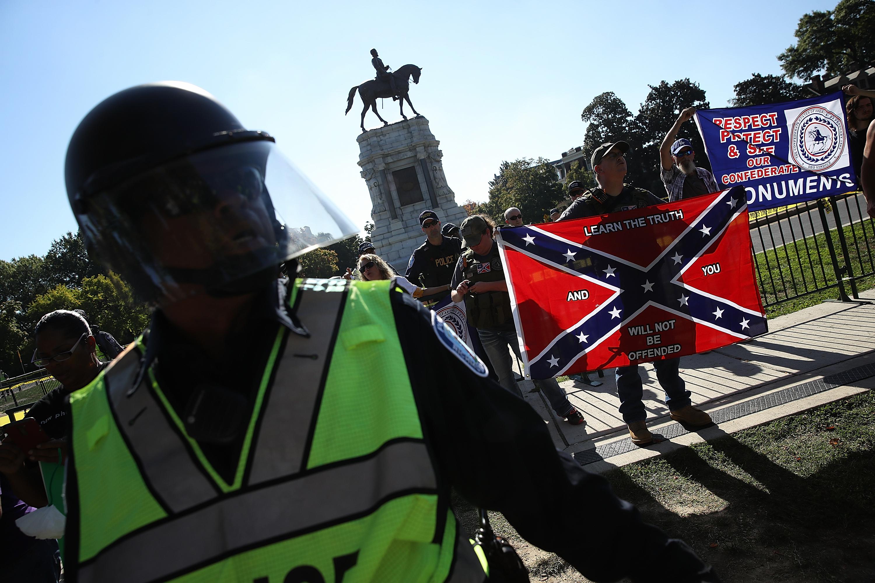 Police separate protesters and counterprotesters in front of a statue of Robert E. Lee.