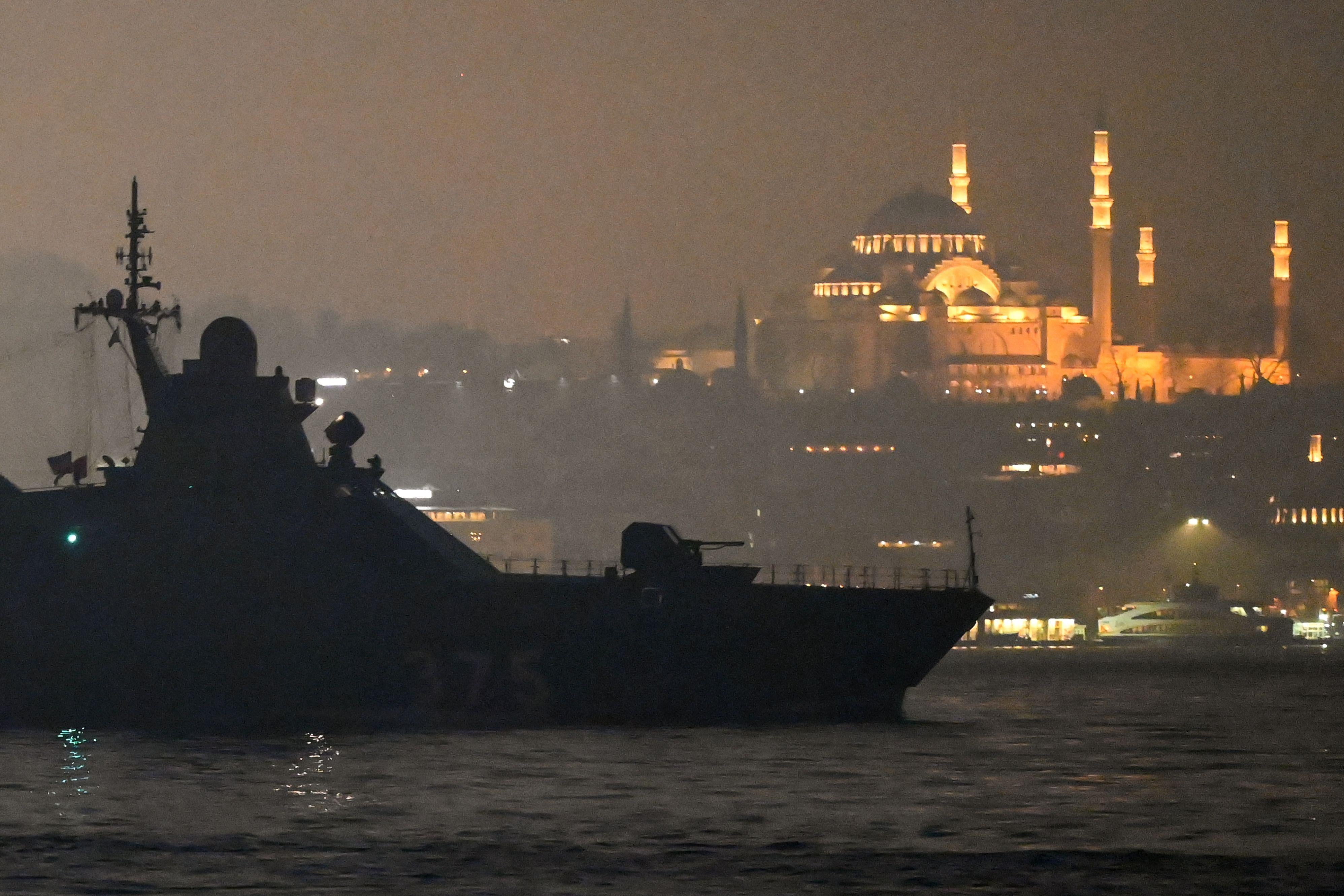 A beautiful mosque lit up as a warship sails by.