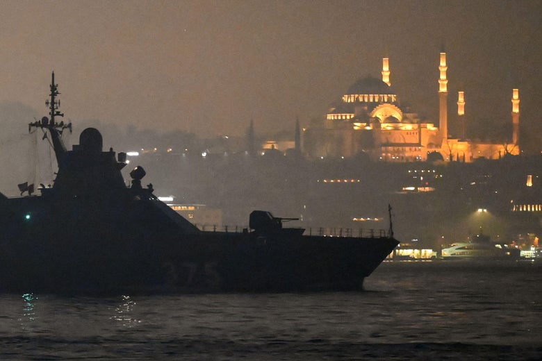 A beautiful mosque lit up as a warship sails by.