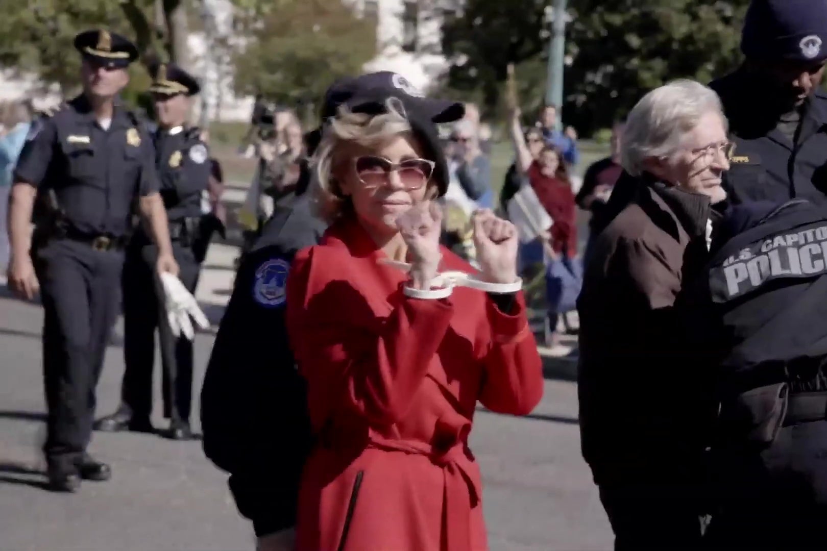 Jane Fonda holding her zip tied hands in front of her at a climate protest.
