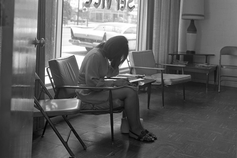 A pregnant girl hides her face as she fills out paperwork at an abortion counseling center.