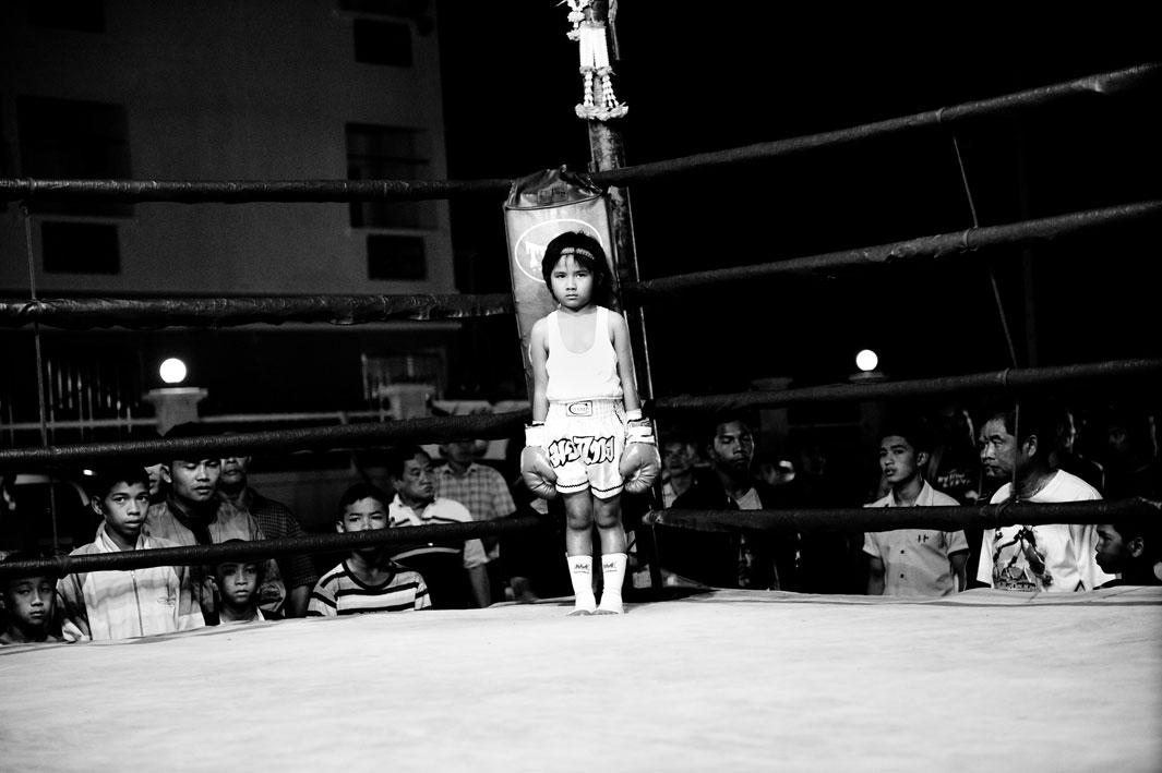 Girl, 6 years, in a boxing ring. Muay Thai (Thai Boxing) is one of the toughest martial arts in the world. A minimum age for the fighters does not exist. For many poor people it secures their livelihood. For a pittance, they reach their mental and physical limits two or three times a month with boxing matches. 