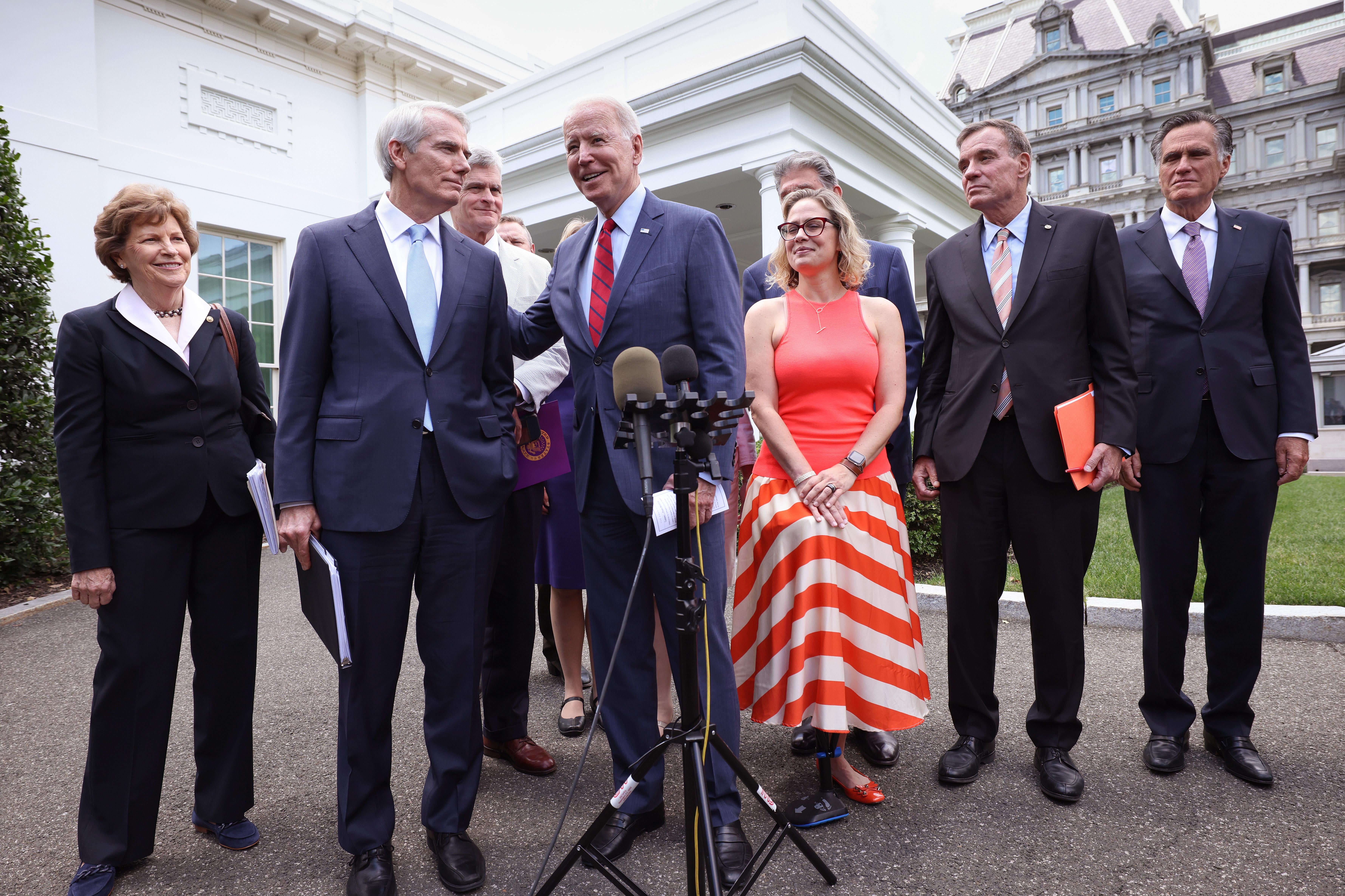 Biden stands smiling with the group in front of the White House