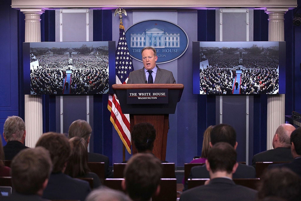 Sean Spicer speaks at the White House press room lectern while flanked by identical pictures of Trump's inauguration crowd taken from a flattering angle.