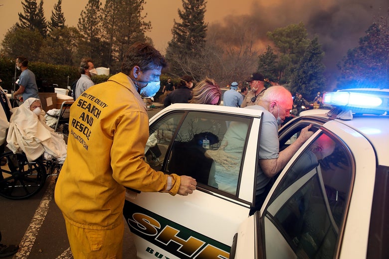 Hospital workers and first responders evacuating patients in a parking lot, with smoke in the background.