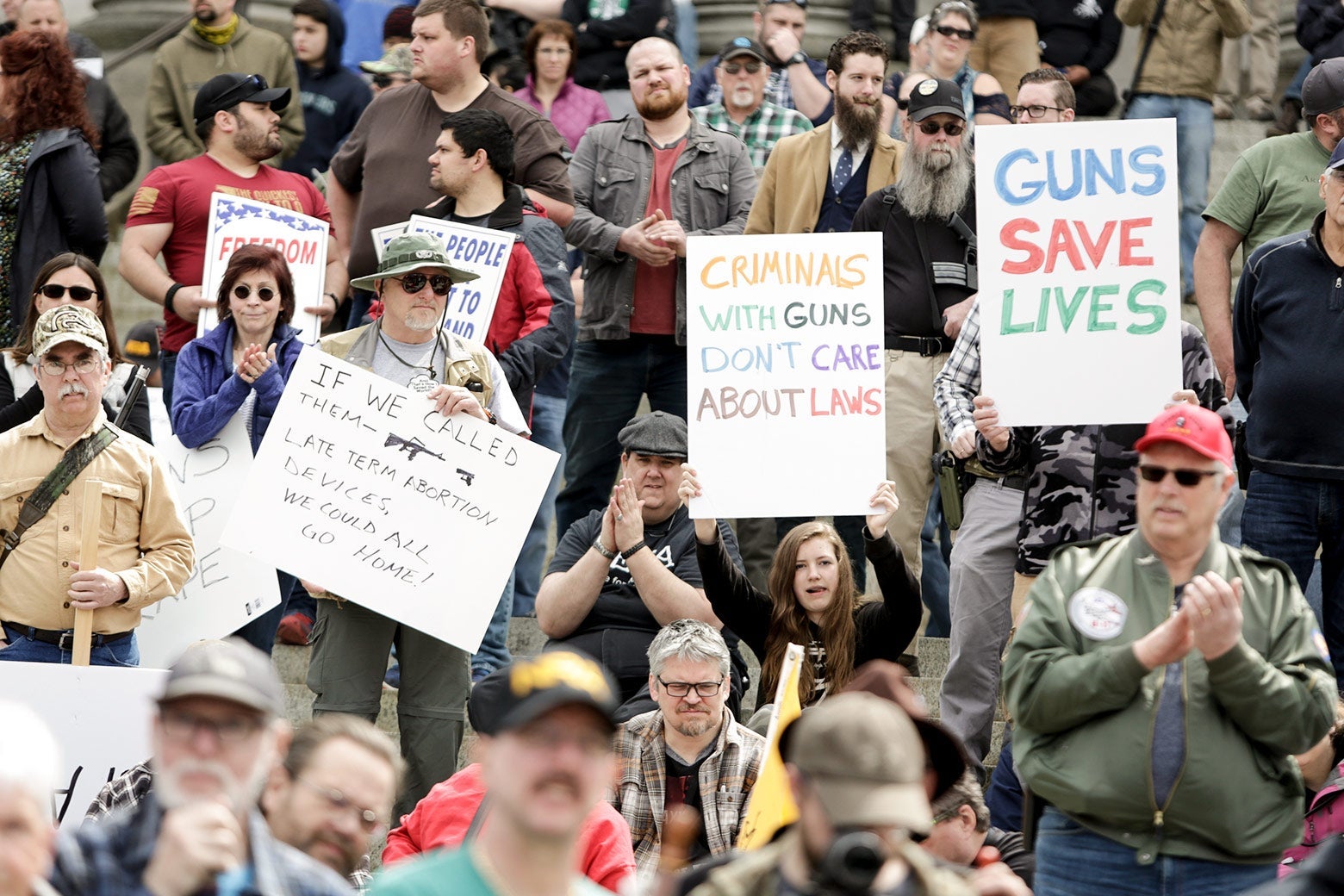 A crowd of gun rights activists holding signs such as "Guns Save Lives" and "Criminals With Guns Don't Care About Laws."