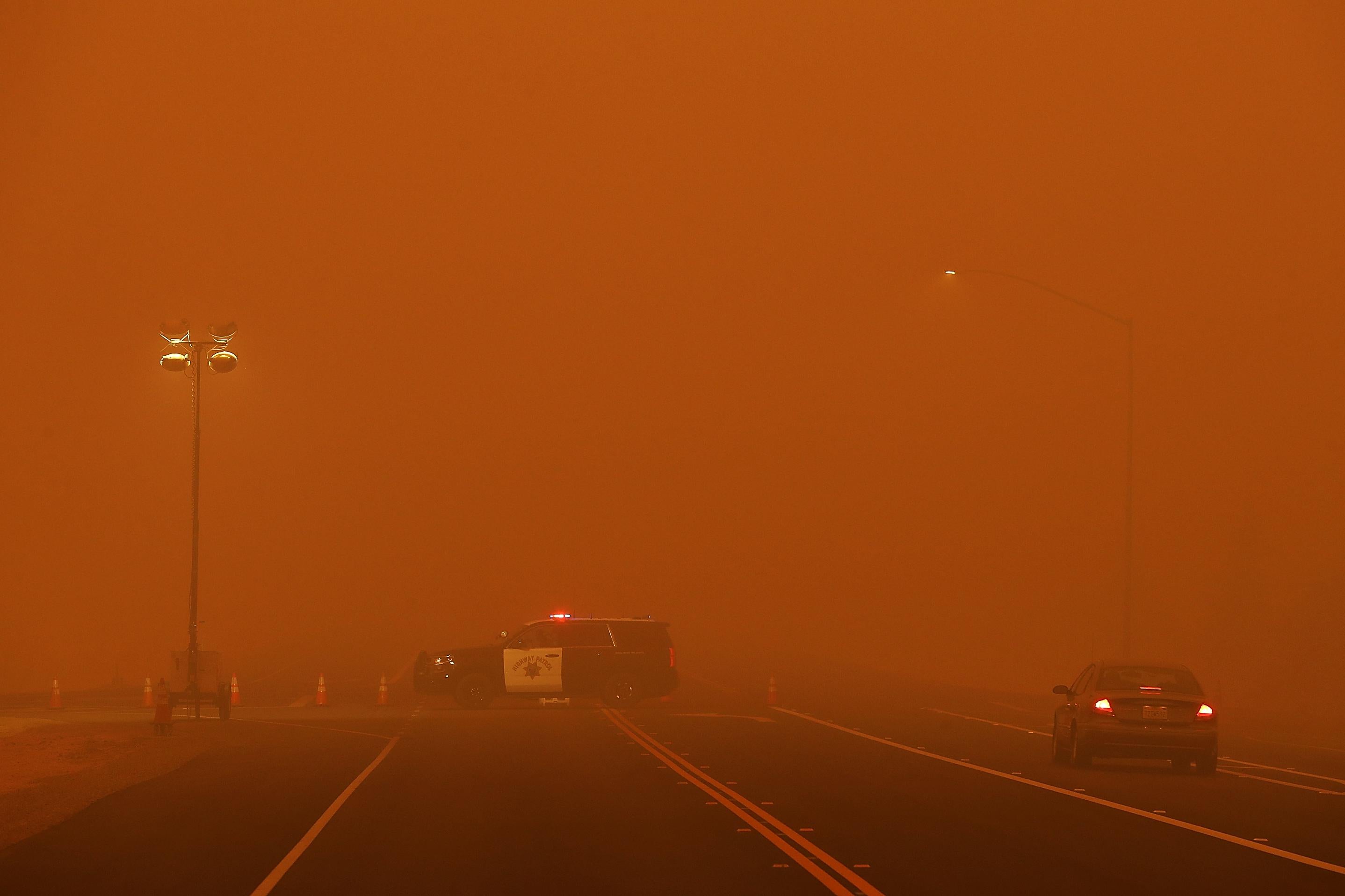 A patrol vehicle on an empty road engulfed in a smoky haze.