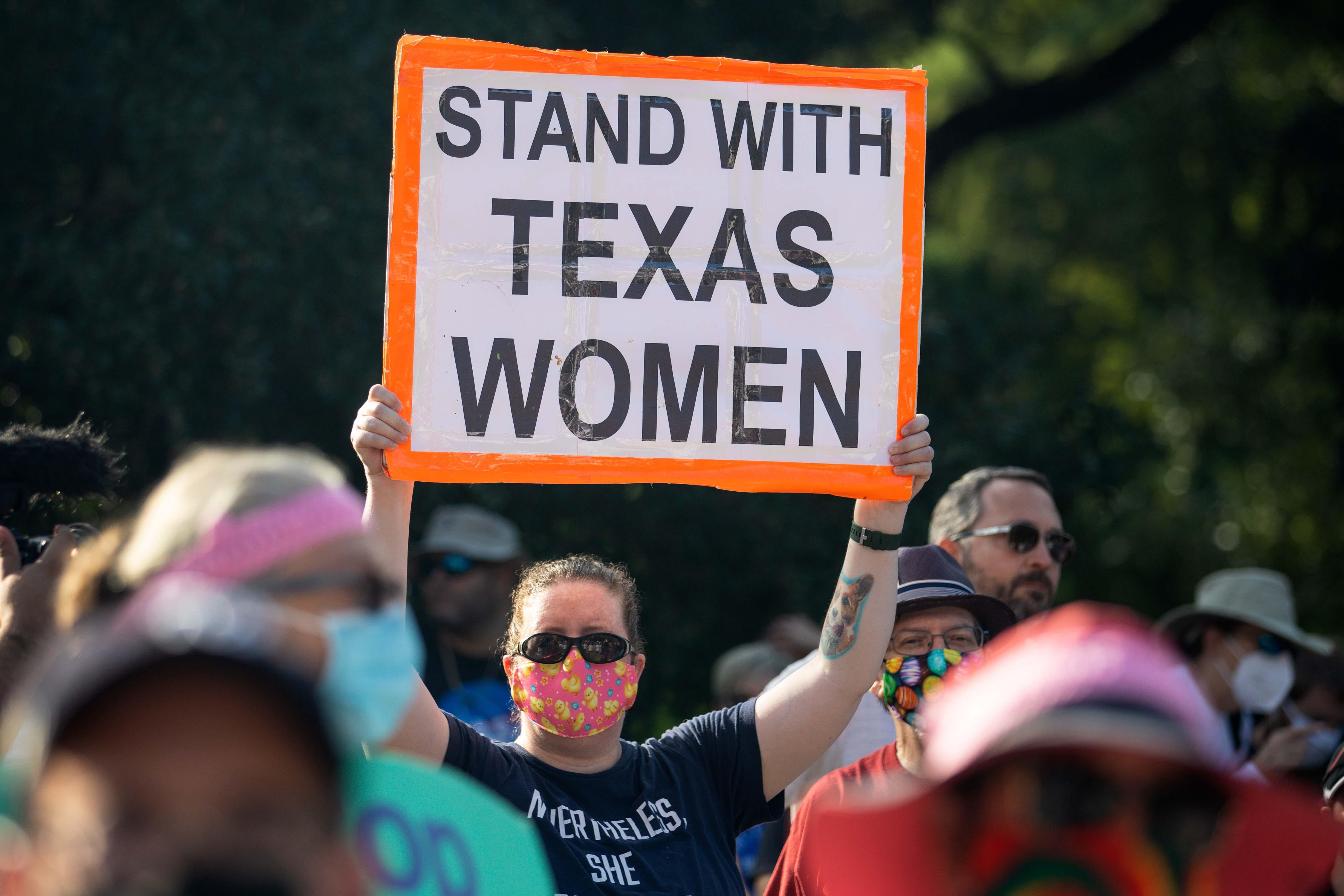 A protester in a crowd holds up a sign that says, "STAND WITH TEXAS WOMEN."