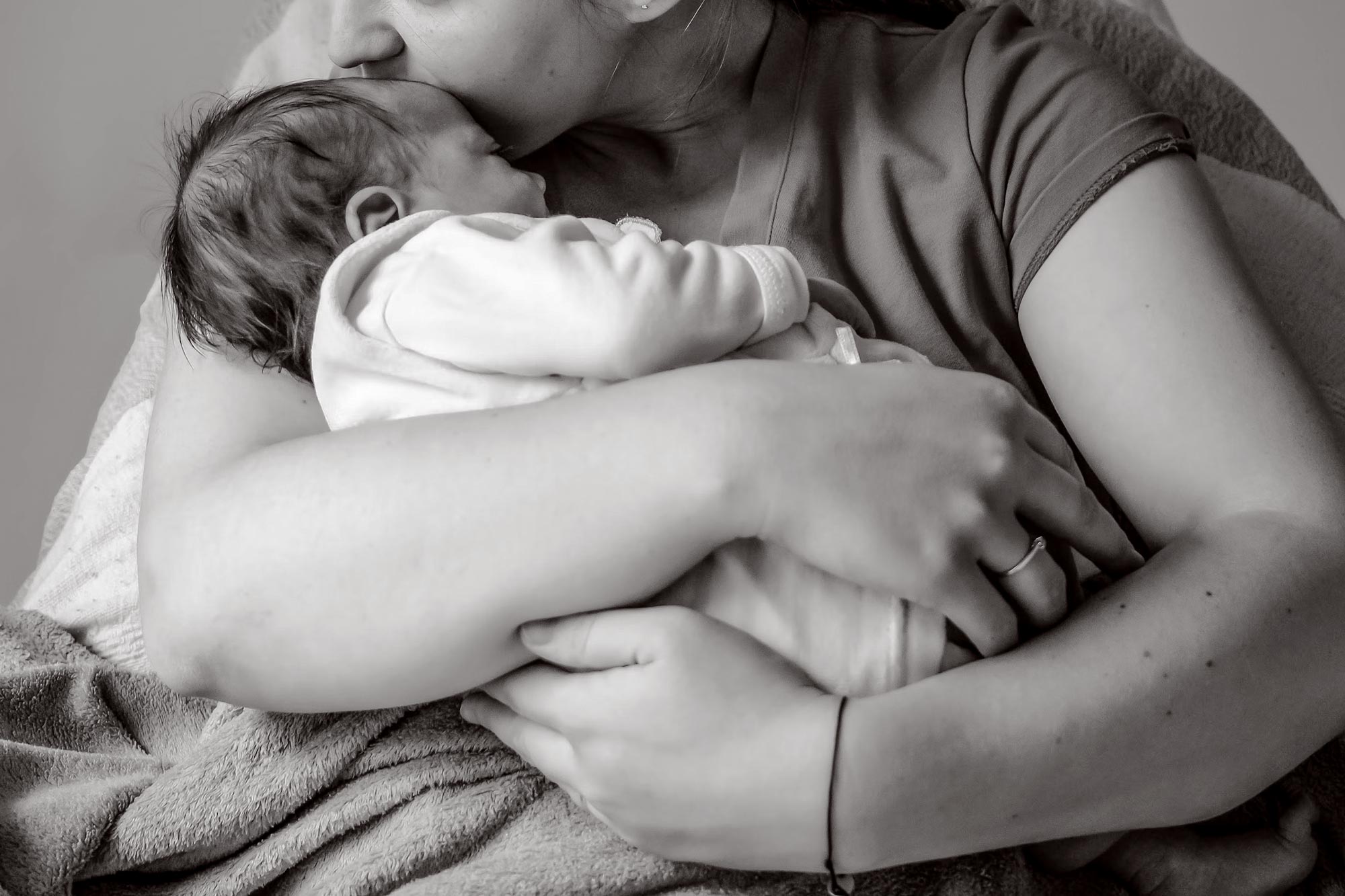 Black-and-white image of a mother holding and kissing an infant.