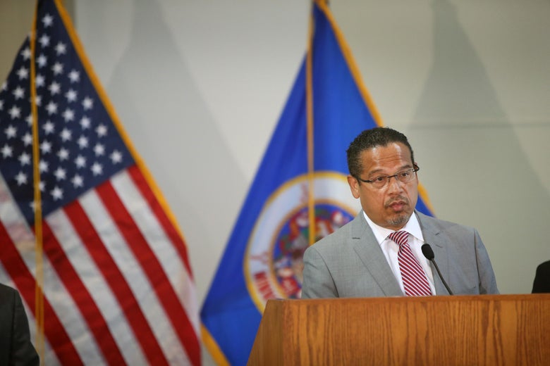 Keith Ellison stands at a podium in front of an American flag and a Minnesota state flag