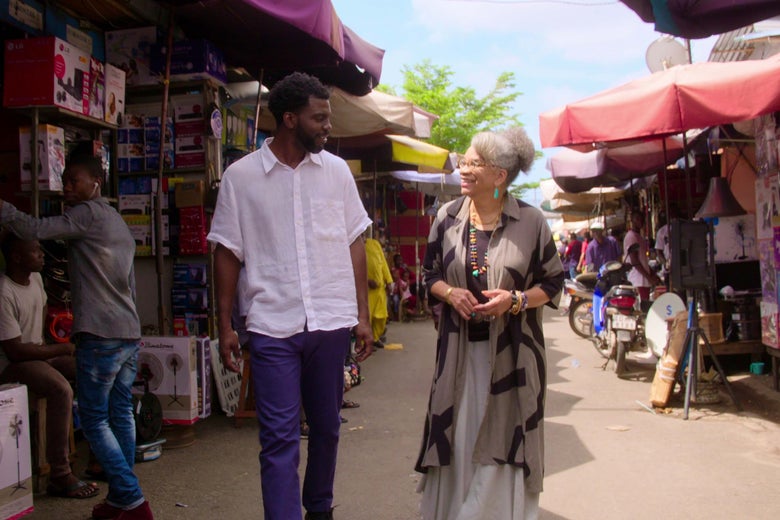 Two people walk through a busy market.