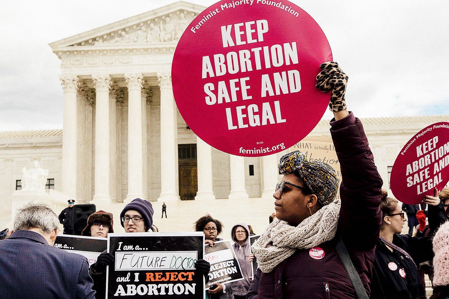 In front of the Supreme Court, a crowd of abortion rights supporters holding signs reading "KEEP ABORTION SAFE AND LEGAL" and anti-abortion activists holding signs reading "I am a future ___ and I REJECT ABORTION."