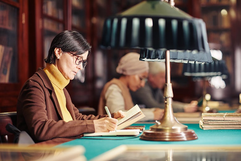 Academics sitting at a table in a library and taking notes