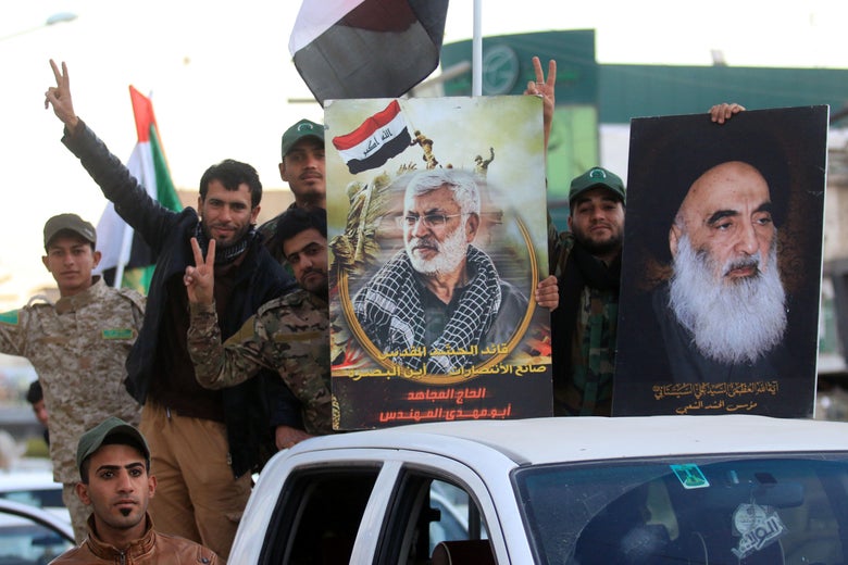 Men smile and flash the victory sign form the back of pickup trucks holding signs showing Sistani and Mohandes.