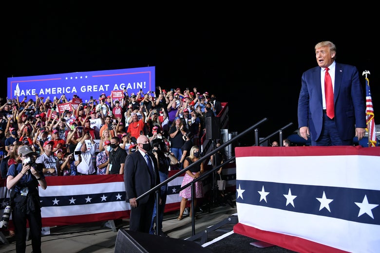 Trump, standing onstage, reacts to a crowd of his supporters